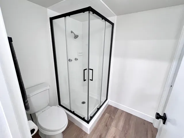 Primary full bathroom featuring wood finished floors, shower, and additional closet space