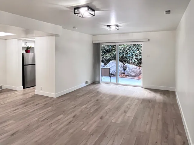 Living room featuring warm tones, fresh wood style flooring and newly painted timeless two-toned paint with large, modern baseboards
