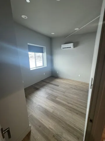 Room featuring light gray walls, recessed ceiling lighting, and wood-finish flooring