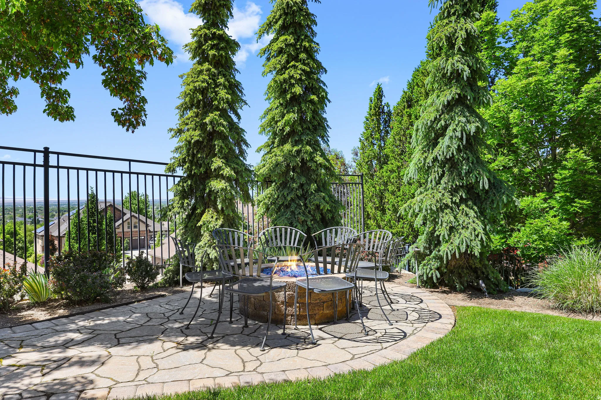 Stone patio featuring a built-in fire pit, surrounded by mature evergreen trees