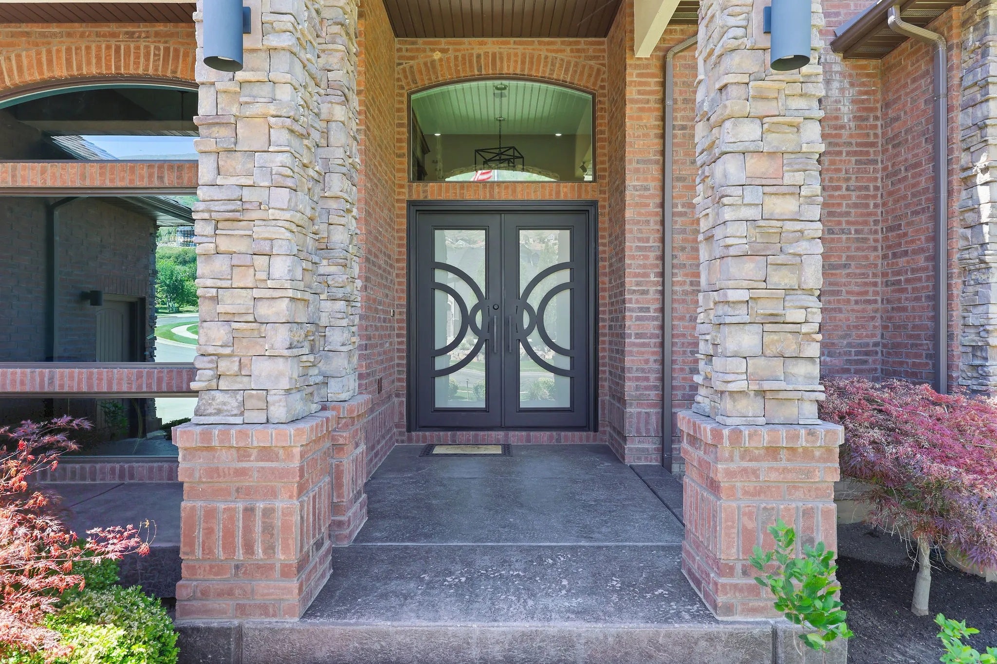 Stately brick and stone exterior featuring a double entry door with decorative glass inserts and an arched transom window