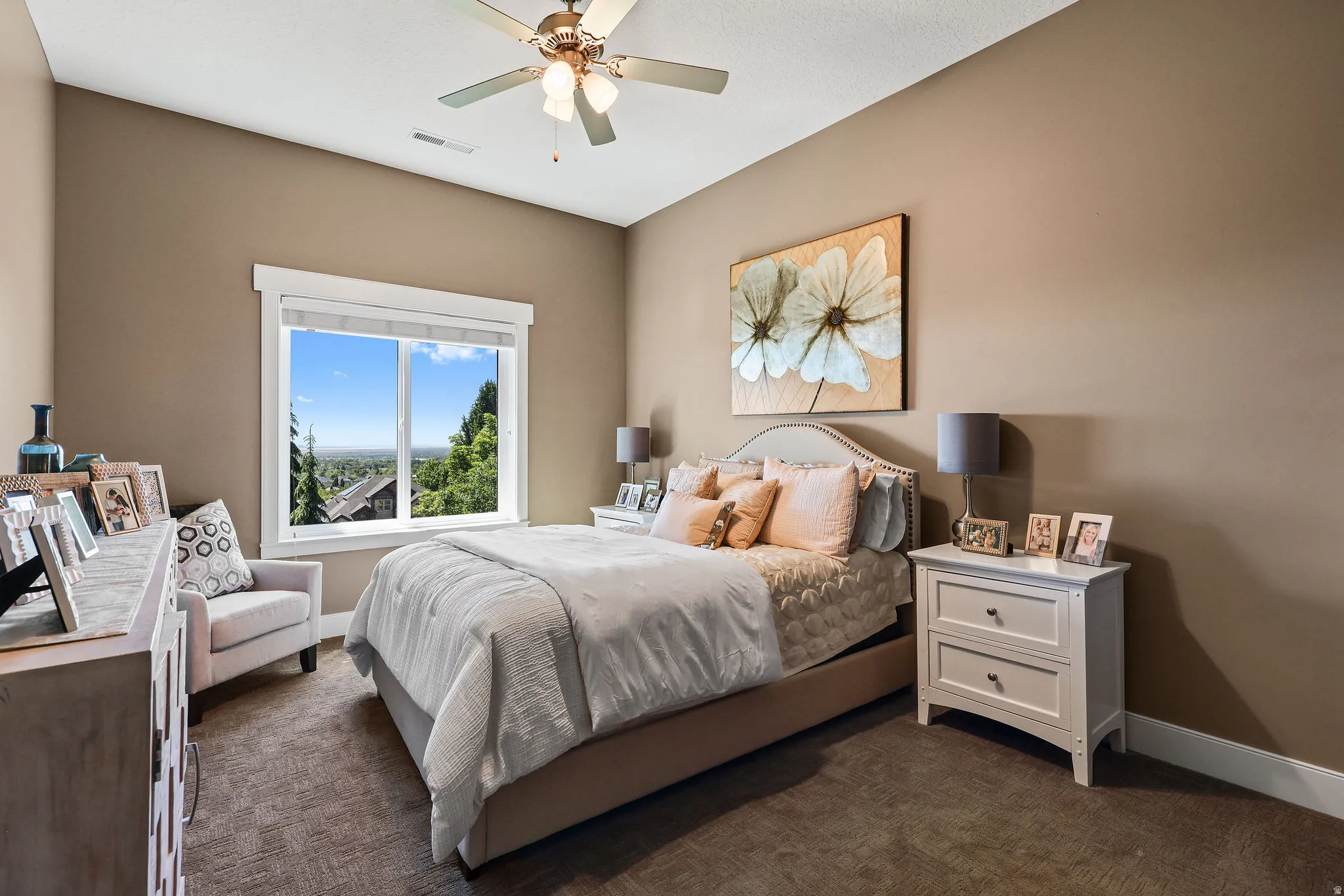 Carpeted bedroom featuring a large window with white trim, a ceiling fan with integrated lighting, and neutral wall tones