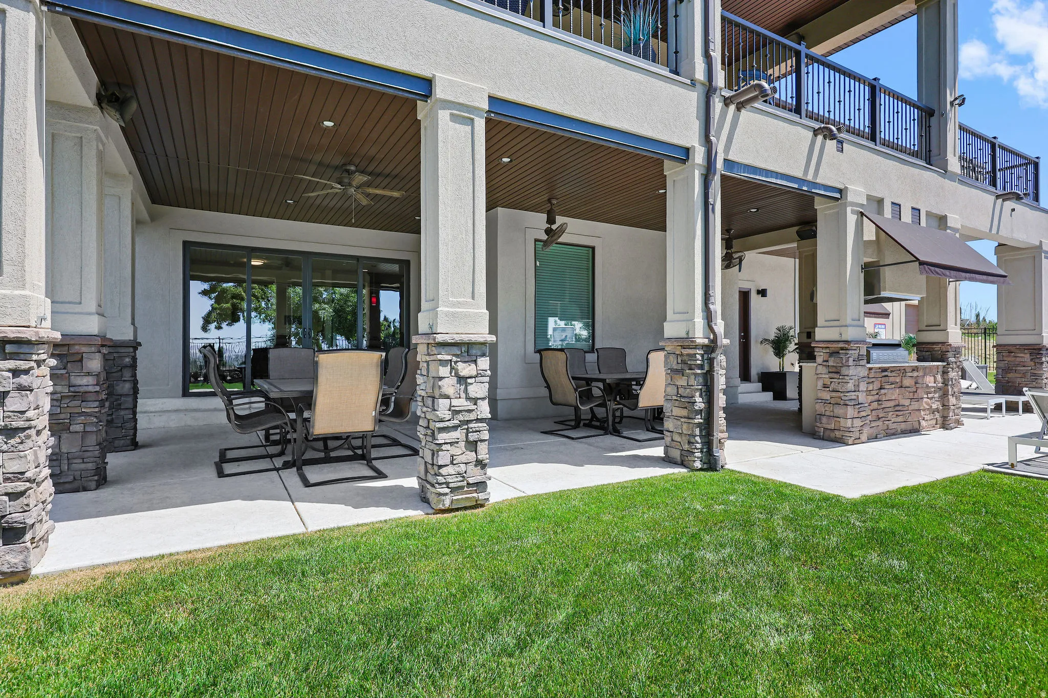 Expansive covered patio featuring a built-in outdoor kitchen, ceiling fans, and recessed lighting
