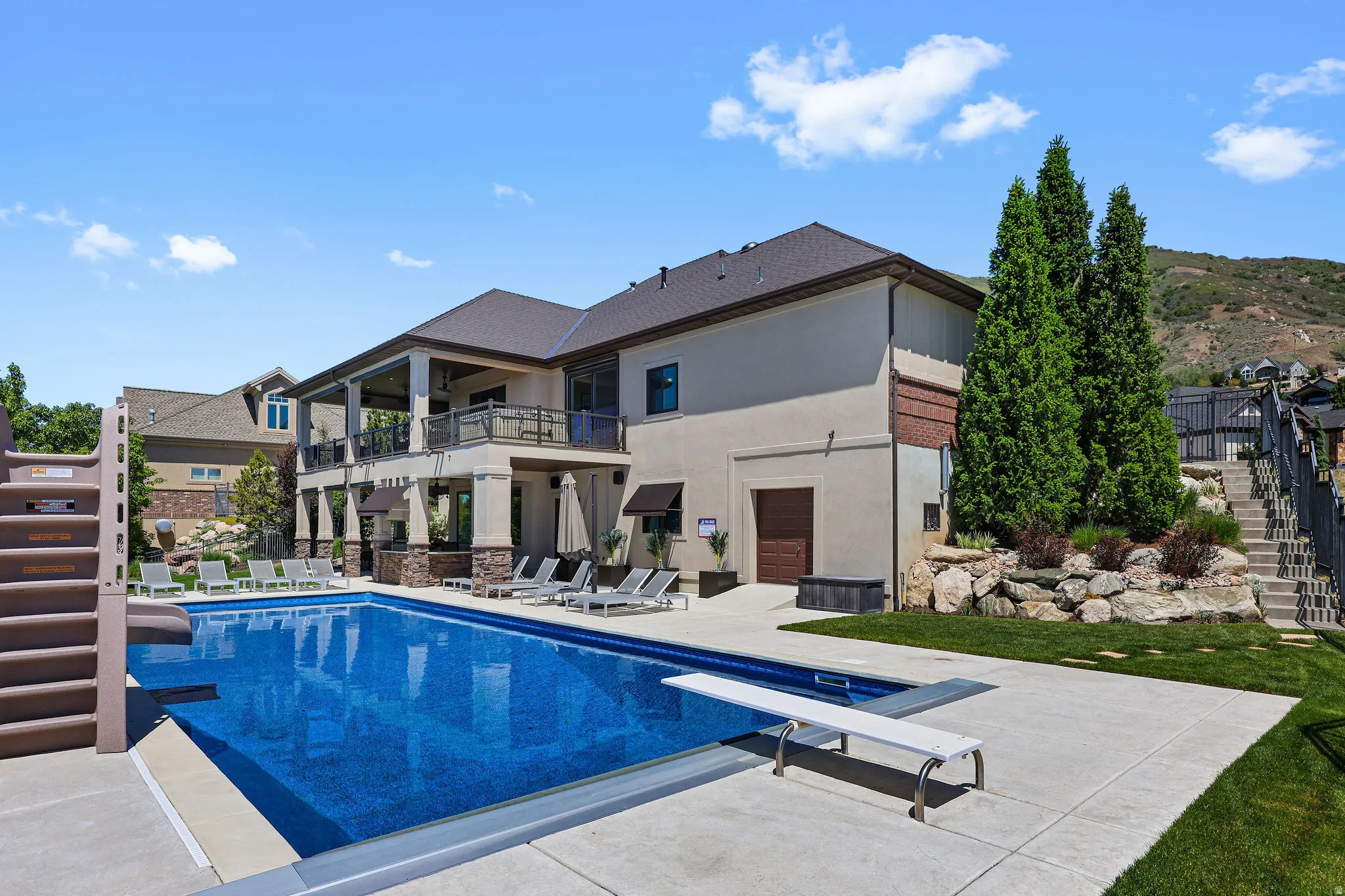 Expansive outdoor pool area with a diving board, concrete decking, and integrated stairs