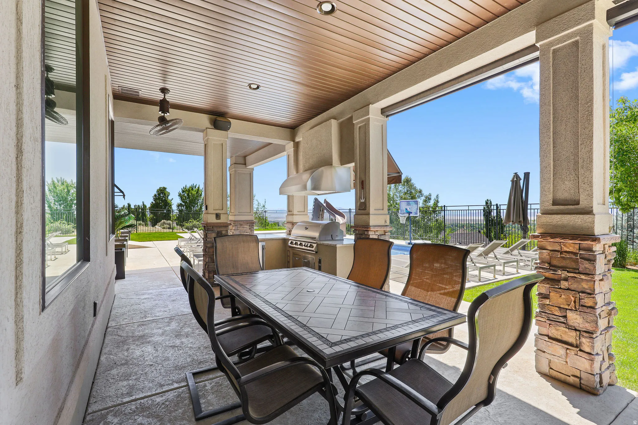 Covered patio featuring an outdoor kitchen with built-in grill and range hood, recessed lighting, ceiling fan, and textured concrete flooring