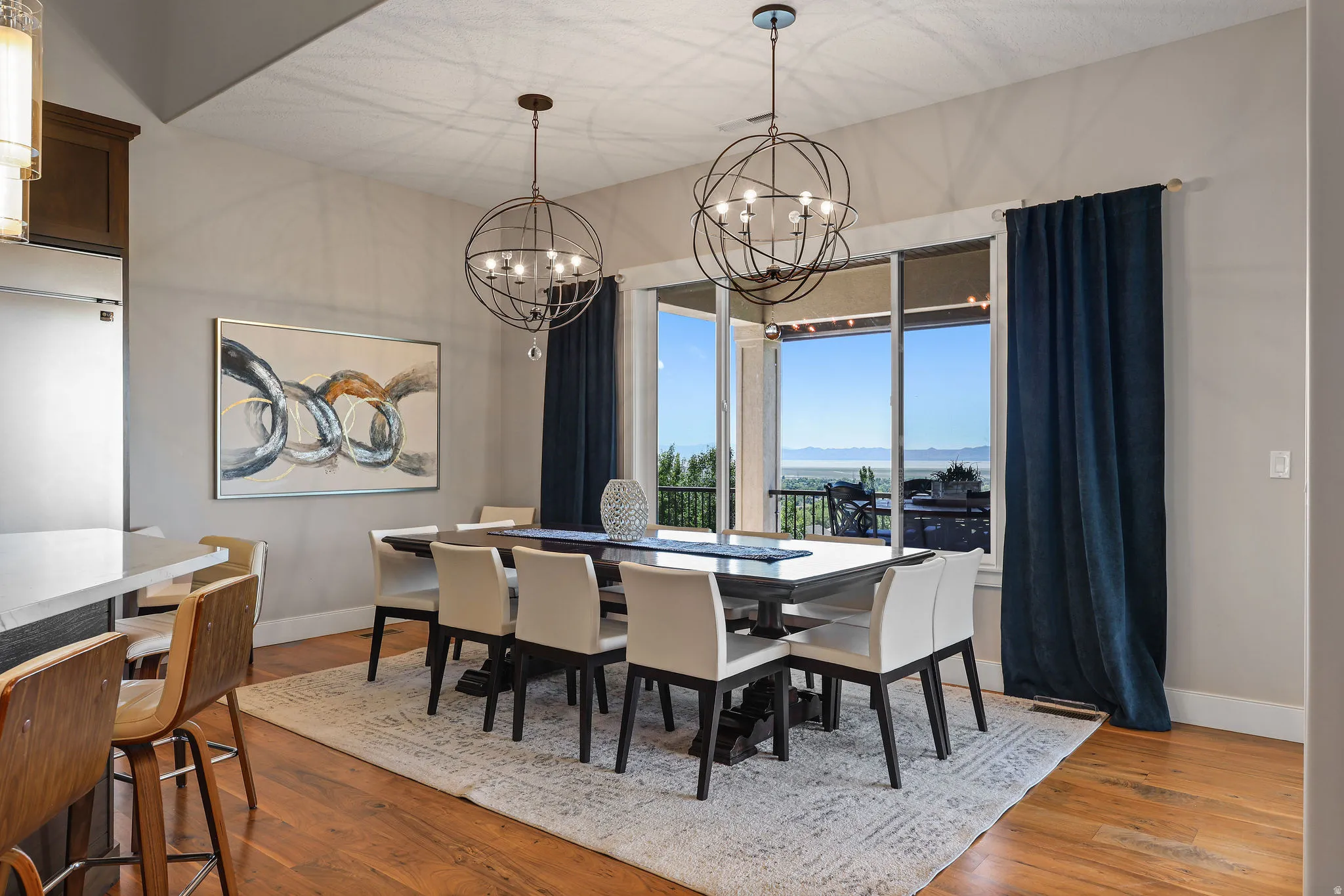 Formal dining area featuring rich wood-finish flooring, a large area rug, and two spherical pendant light fixtures