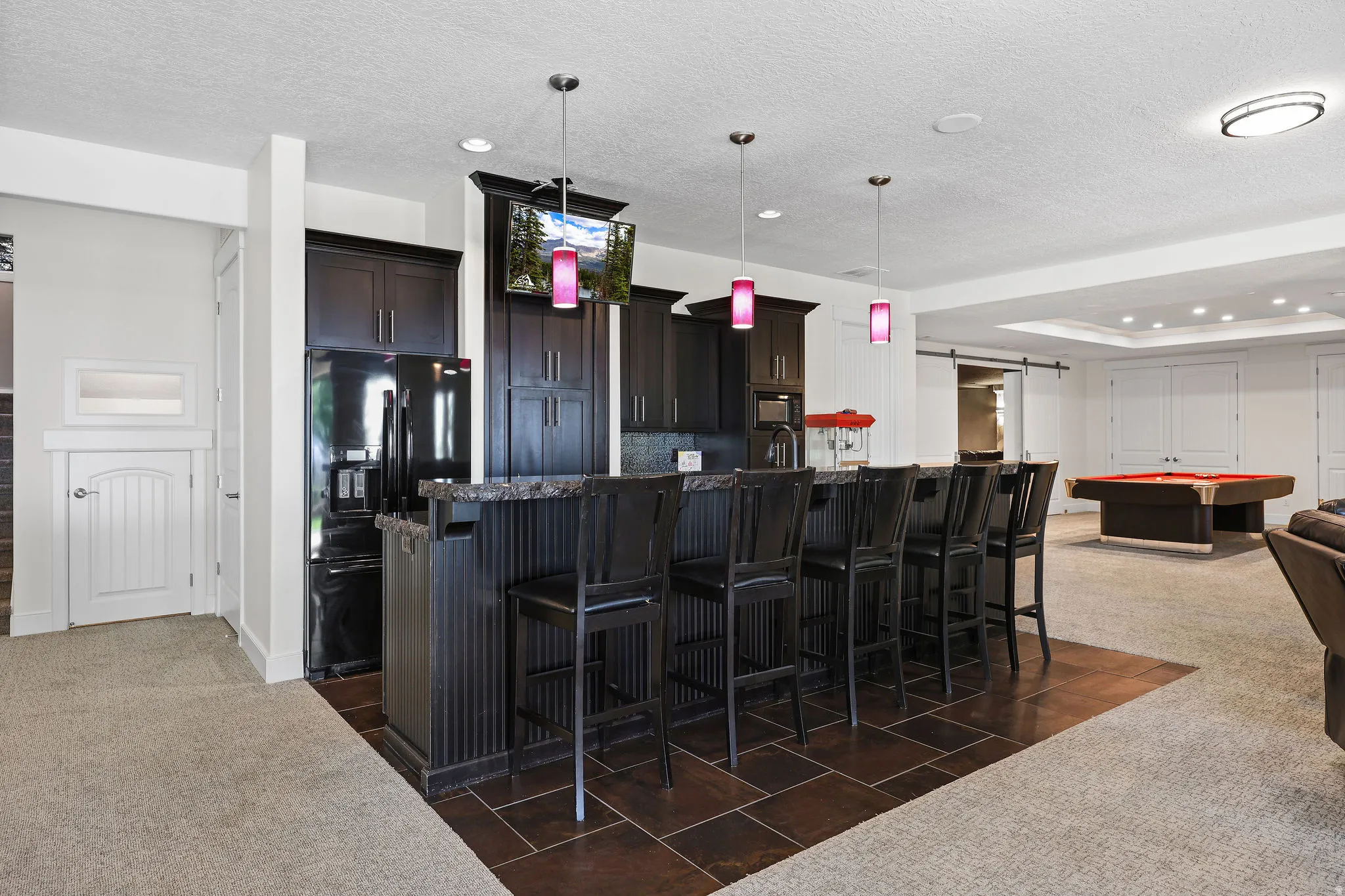 Entertainment space featuring a dark wood-finish bar with seating for six, dark cabinetry, and integrated appliances