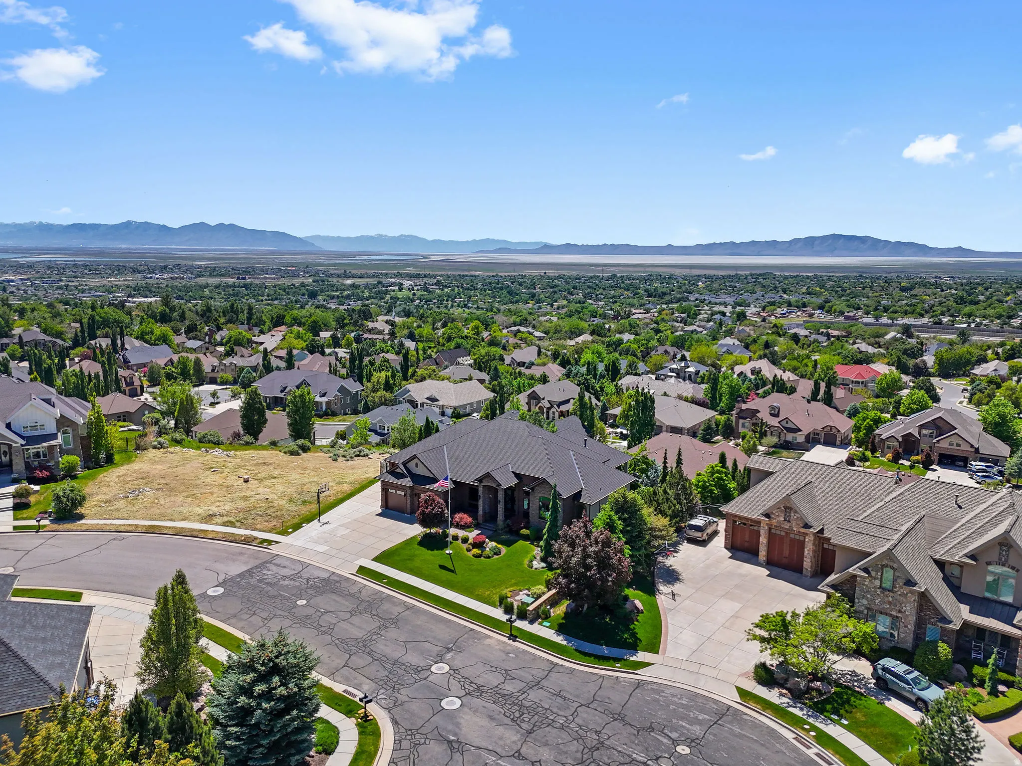 Expansive residential area featuring numerous properties amidst extensive greenery and distant mountain ranges