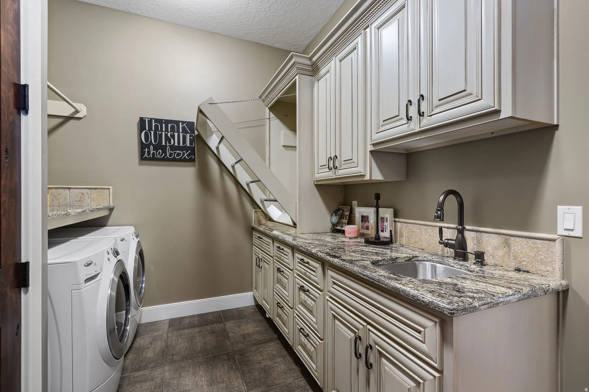 Dedicated laundry room featuring wood-finish flooring and a stone countertop