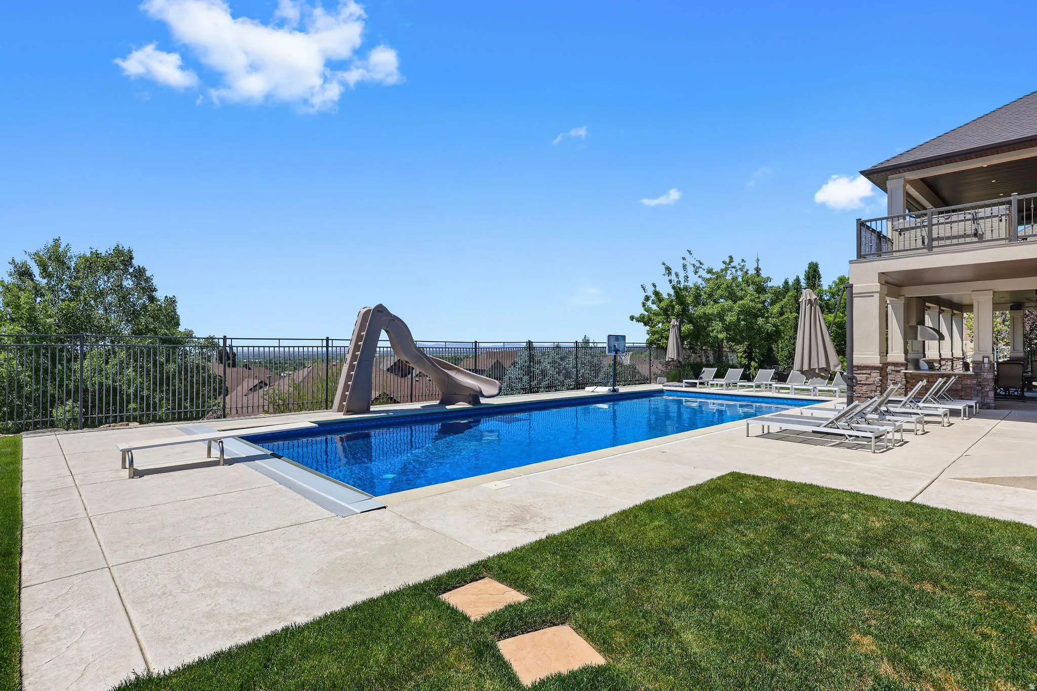 Outdoor swimming pool featuring a diving board and waterslide