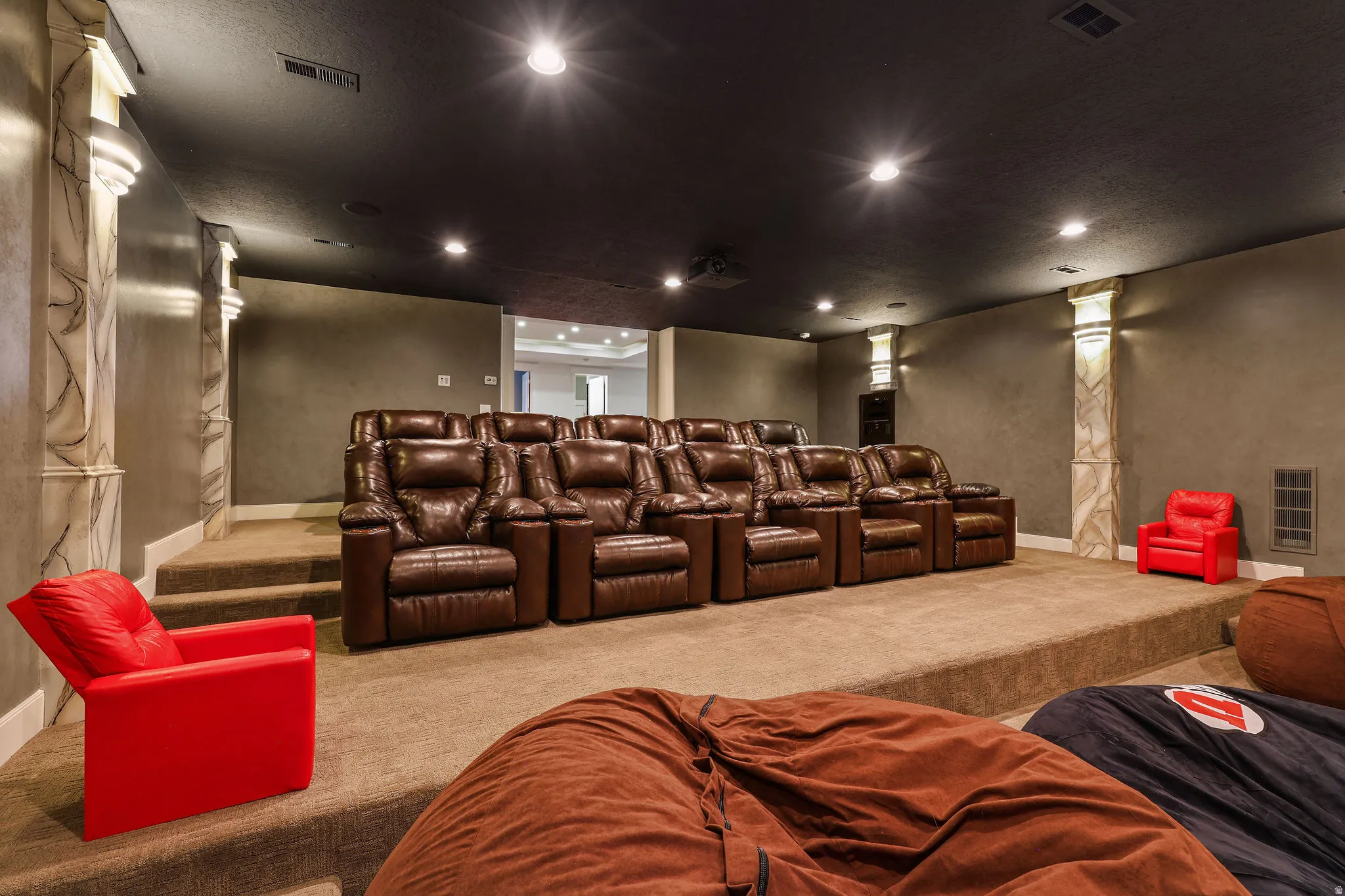 Dedicated media room featuring tiered seating, recessed lighting, and wall sconces