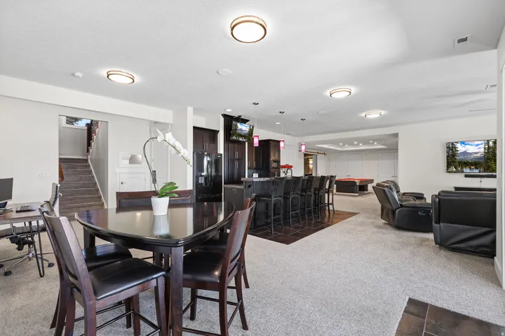 Expansive recreation room featuring a built-in wet bar with pendant lighting, integrated cabinetry, and dark tile flooring