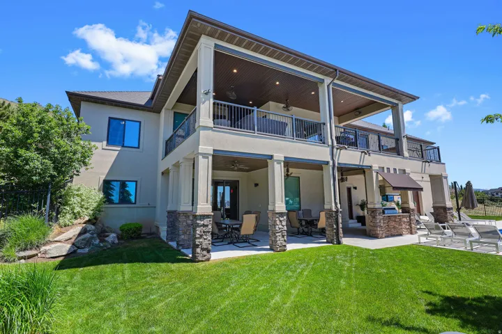 Multi-level exterior featuring covered patios, covered balconies with wrought iron railings, and stone-clad columns