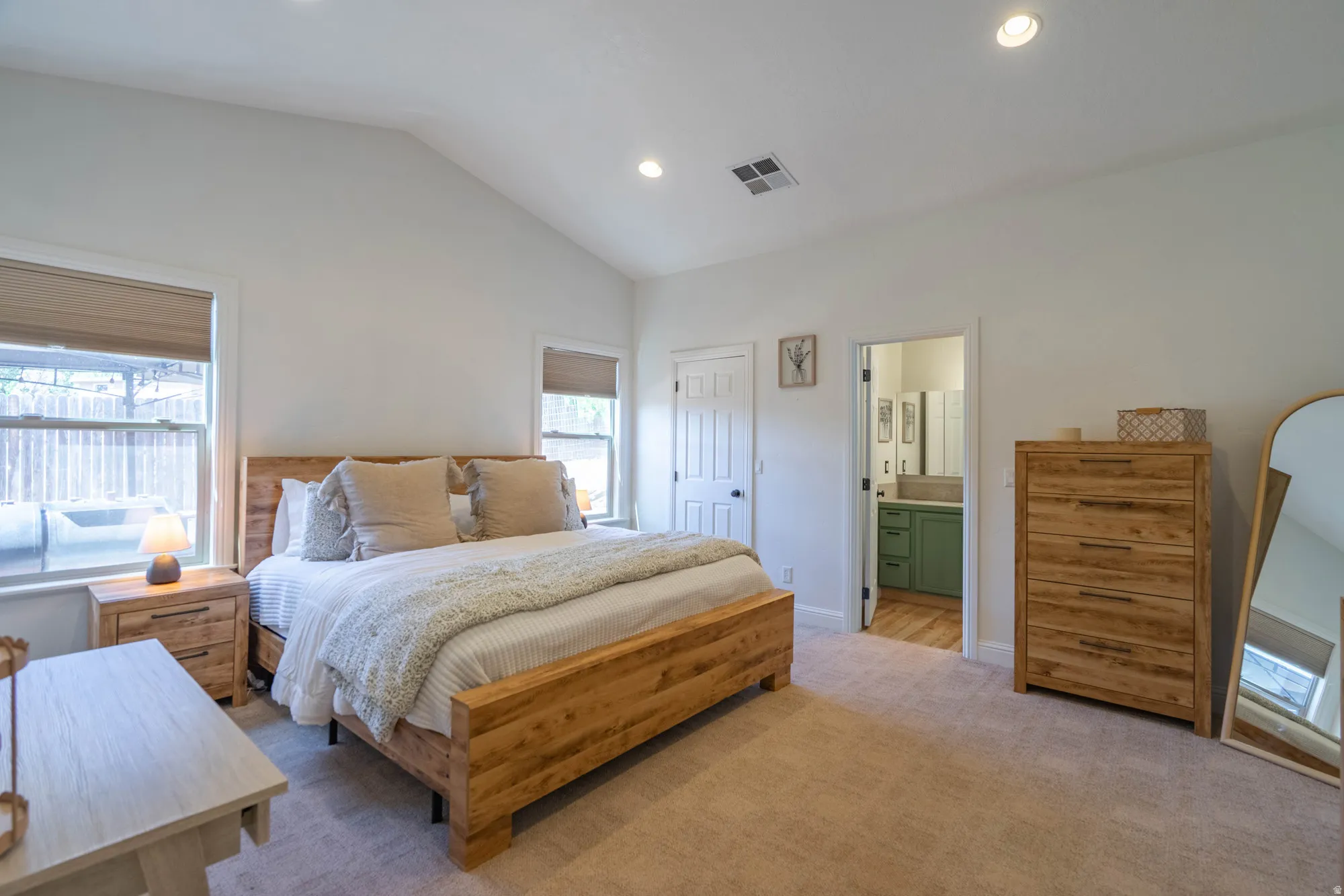 Carpeted bedroom featuring vaulted ceilings, recessed lighting, and dual windows with shades