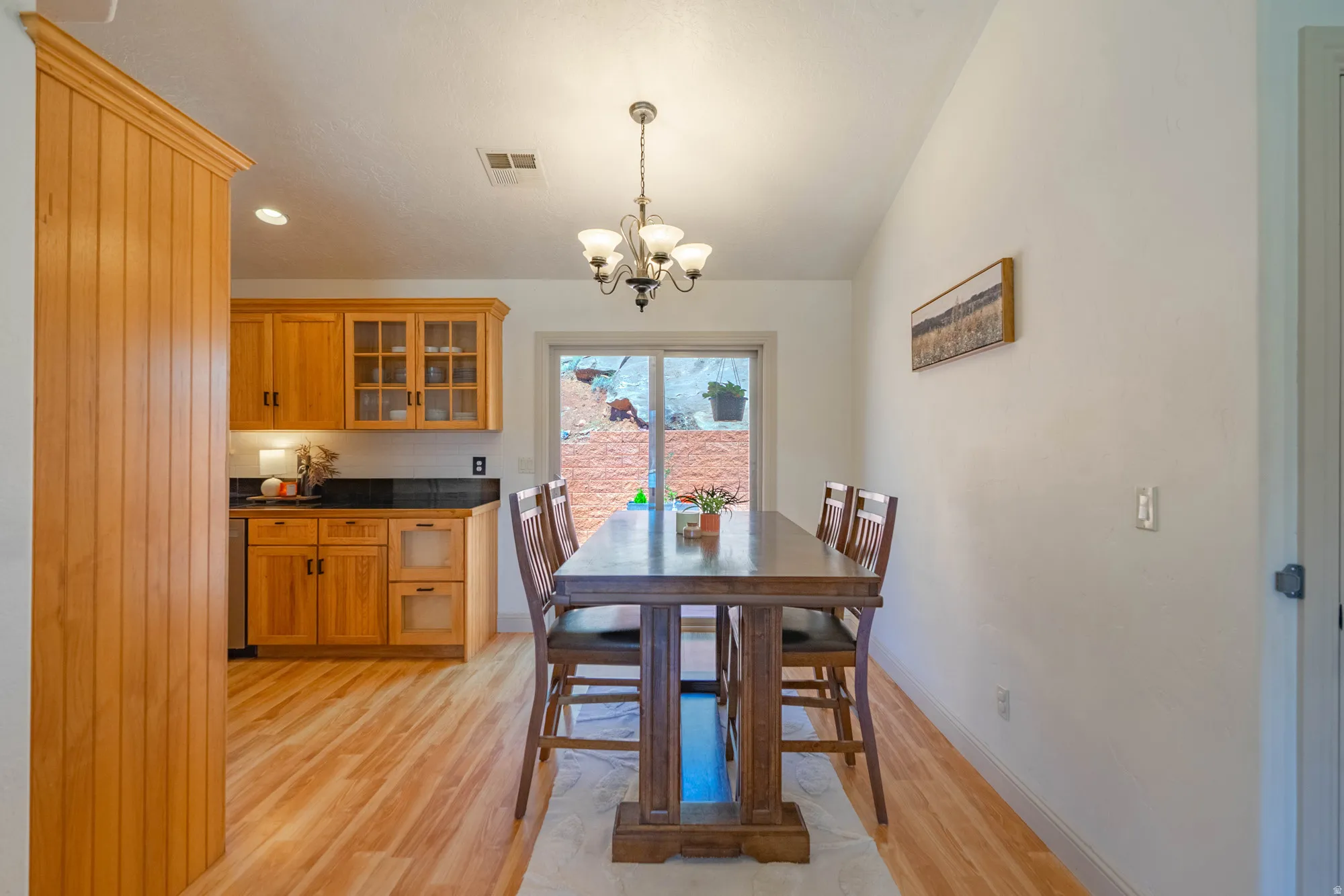 Open concept dining area featuring wood-finish flooring and a contemporary chandelier