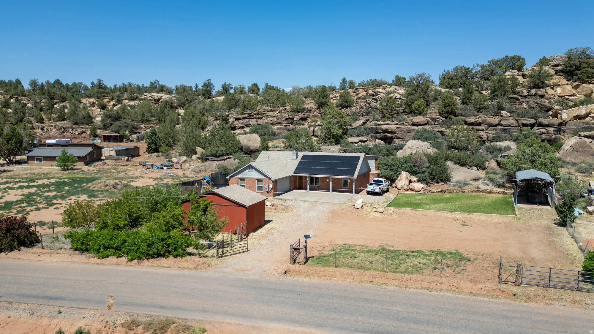 Single-story residence featuring a covered front porch, integrated solar panels, and a red detached outbuilding