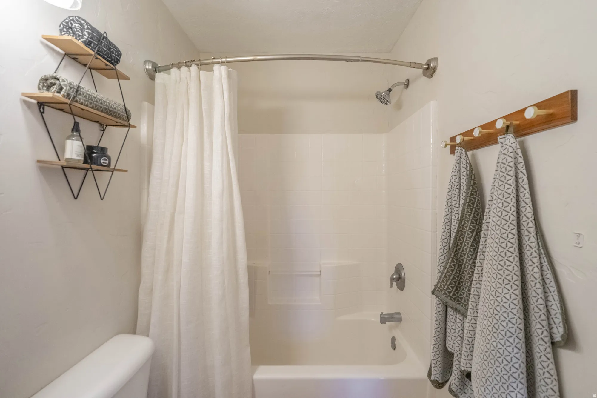 Tub/shower combination featuring a curved shower rod and brushed nickel fixtures