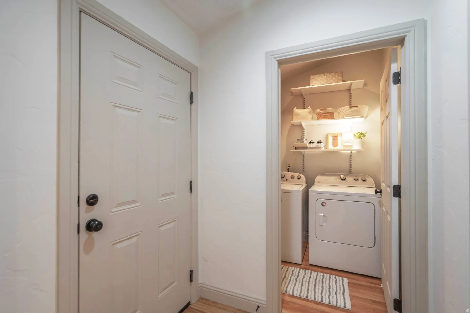 Dedicated laundry area featuring white appliances and wall-mounted shelving for organization