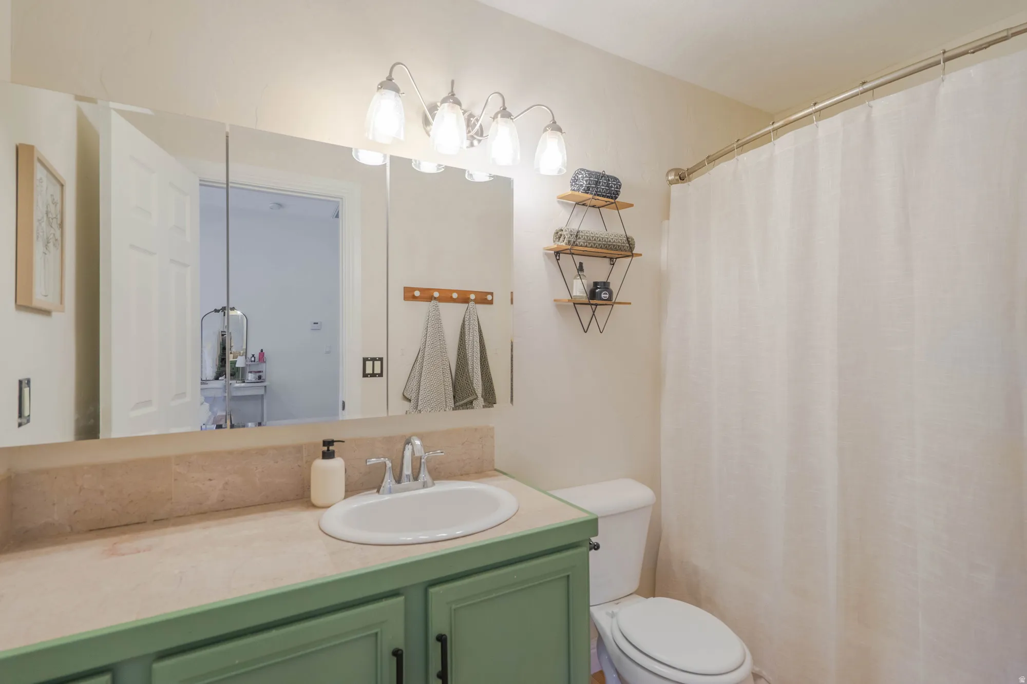 Bathroom featuring a vanity with a white oval sink, green cabinetry, and a light-toned countertop