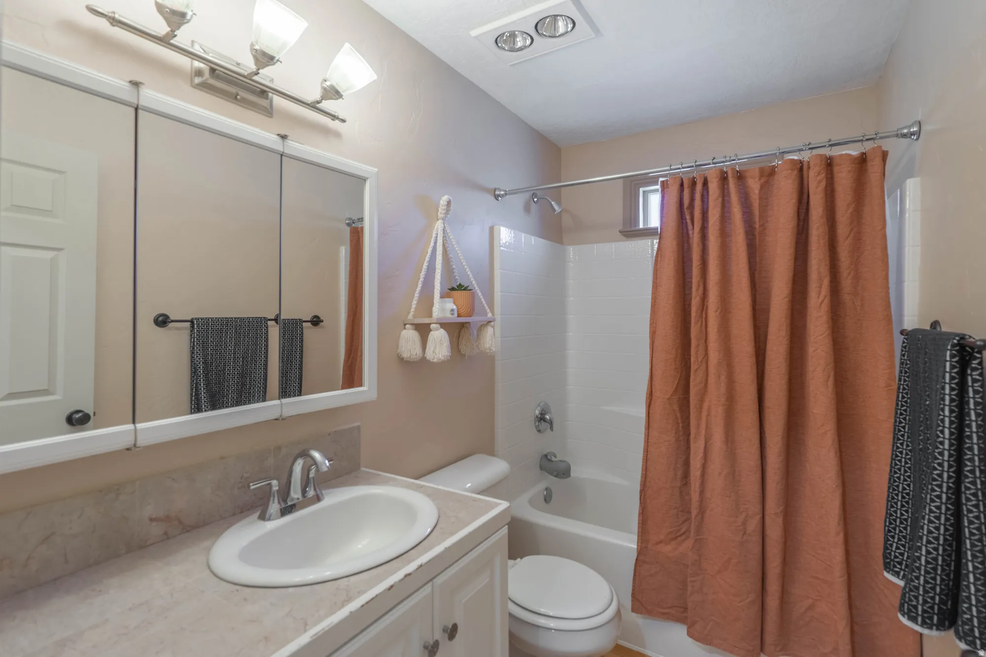 Bathroom featuring a single vanity with a laminate countertop, built-in medicine cabinet, white toilet, and tub/shower combination with white subway tile surround