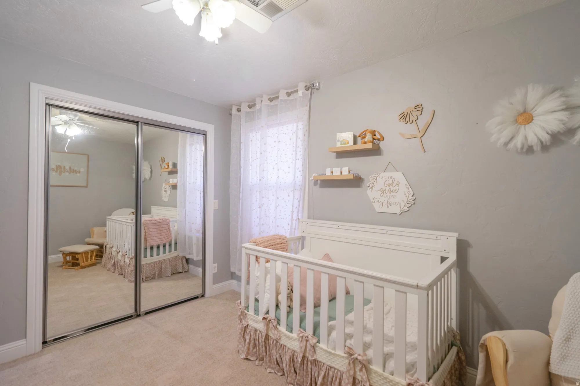 Bedroom featuring mirrored sliding closet doors, a ceiling fan with light fixture, carpeted flooring, and a window with sheer curtains