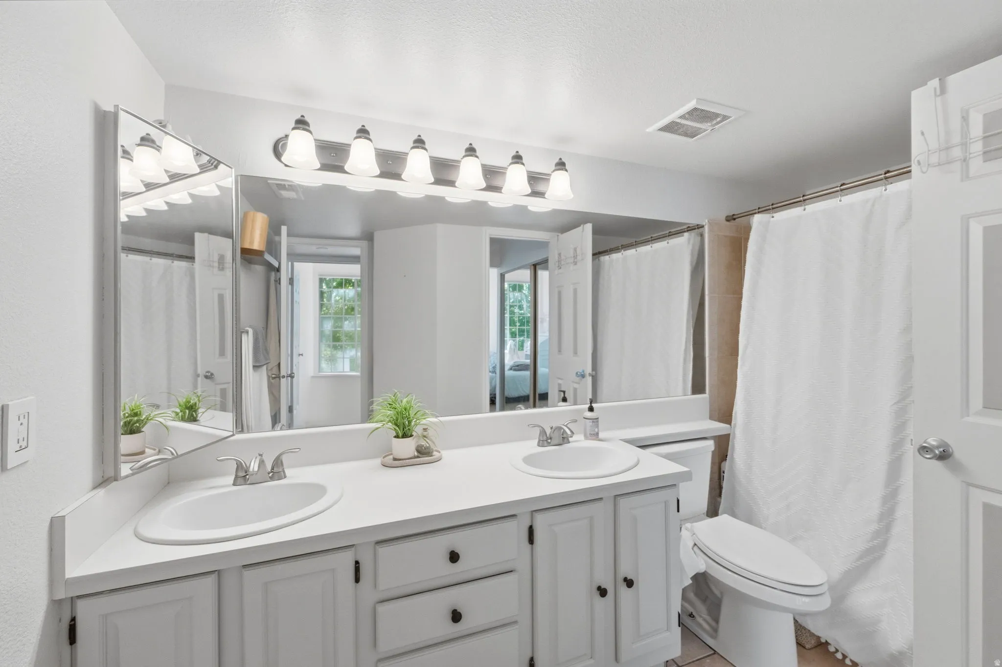 Bathroom featuring a dual-sink vanity with white cabinetry and a full-width mirror