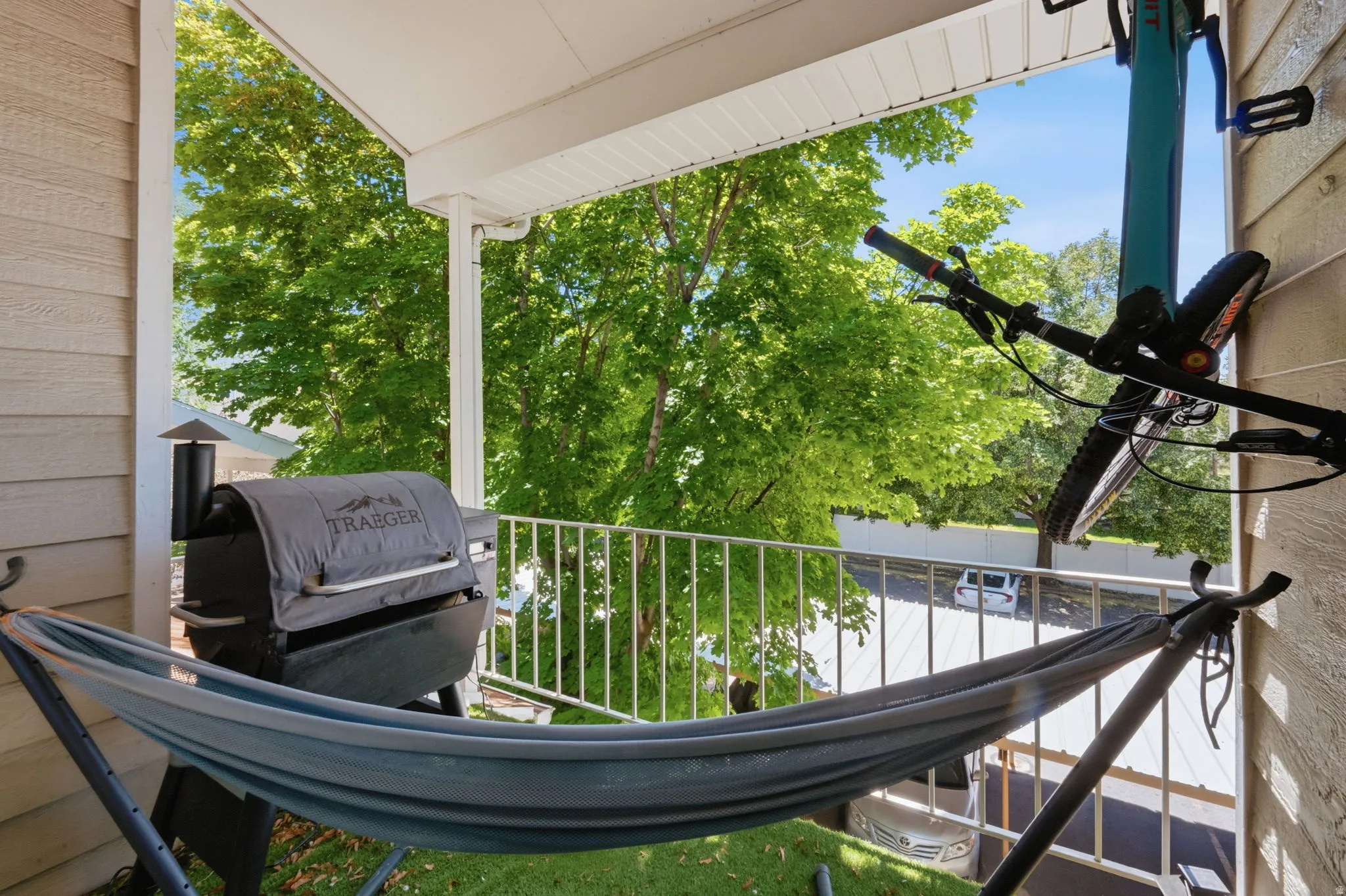 Covered outdoor balcony featuring a white metal railing and tan siding