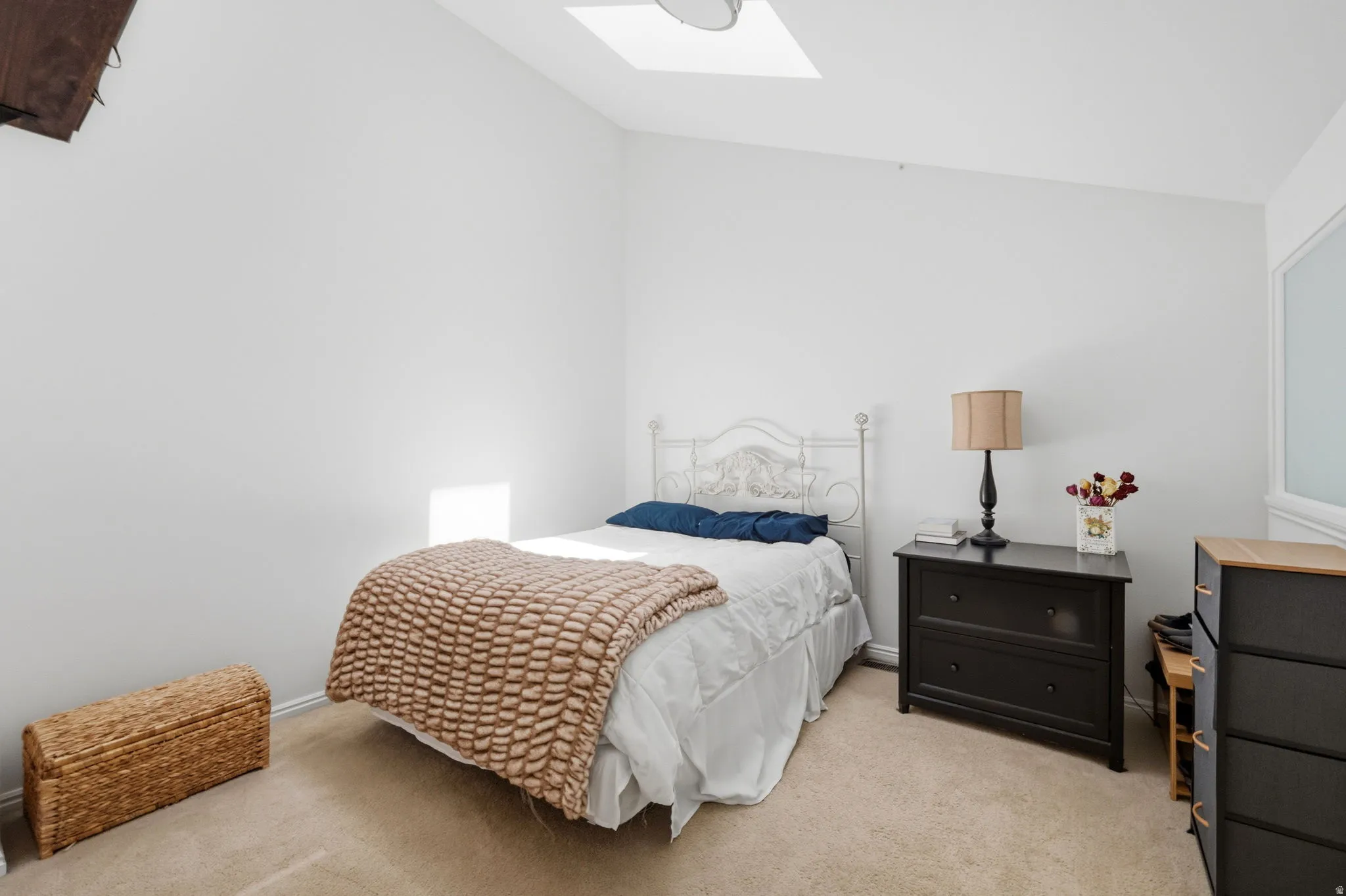Carpeted room featuring a white painted vaulted ceiling, a skylight, and white walls