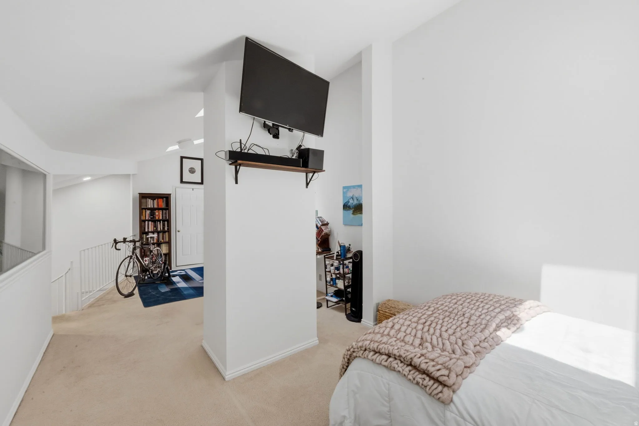 Bright interior space featuring a wall-mounted television, a built-in shelf, and a doorway with a decorative frame