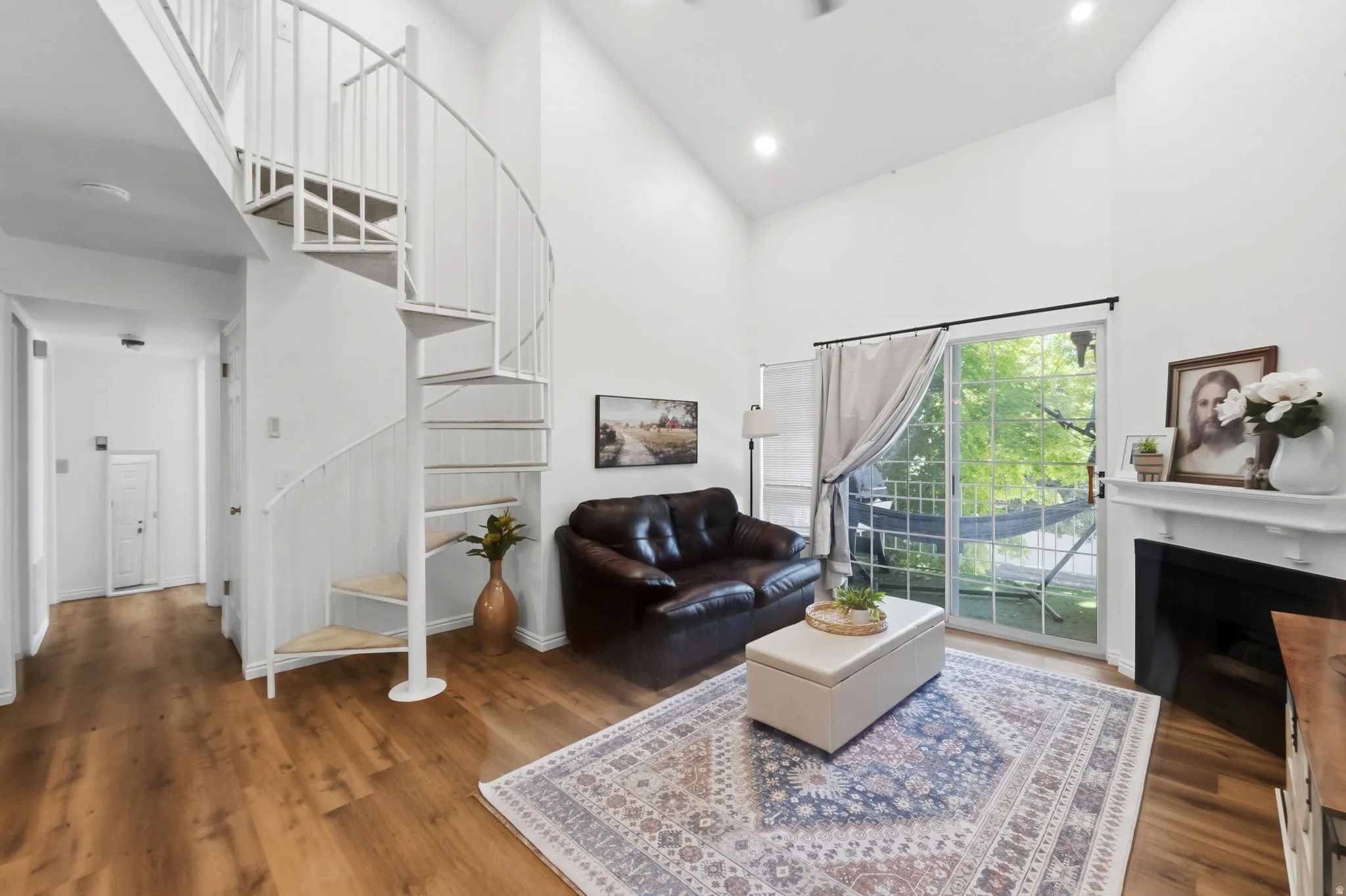 Living space featuring a white spiral staircase, vaulted ceilings, and wood-finish flooring