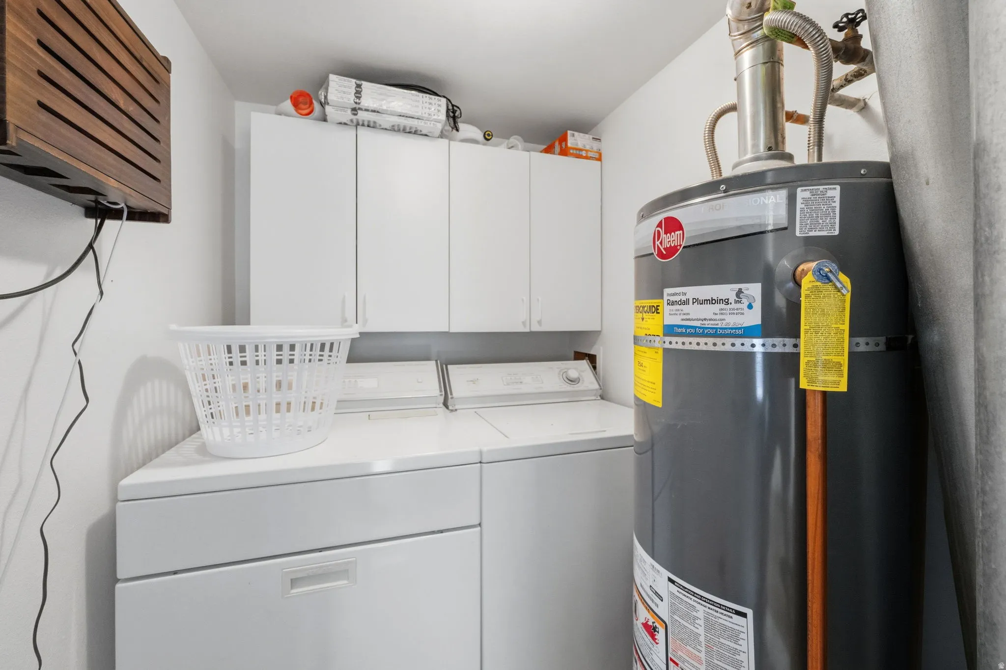 Dedicated laundry area featuring white cabinetry, a built-in countertop, and a water heater