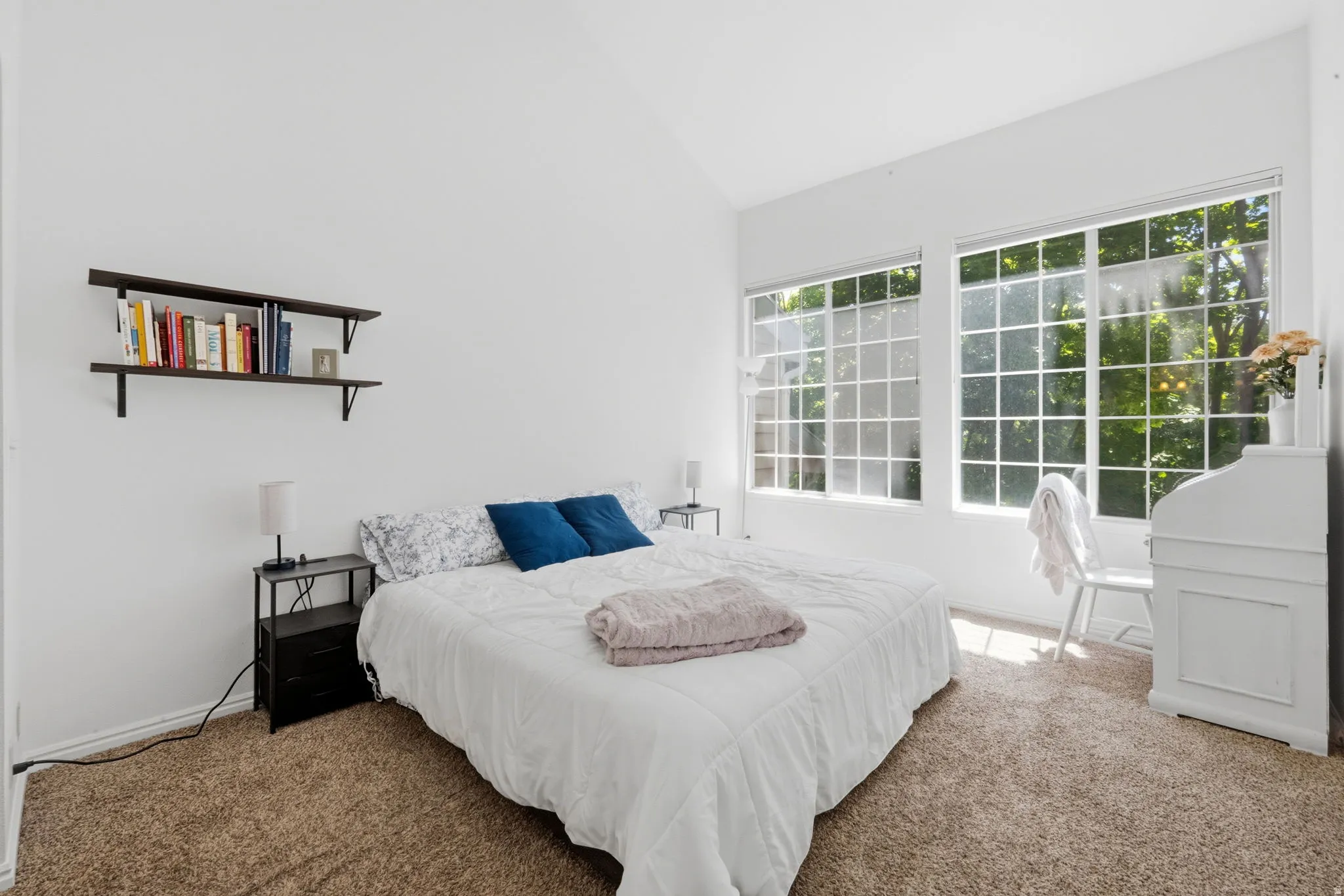 Vaulted ceiling with white walls, carpet flooring, and two large multi-pane windows