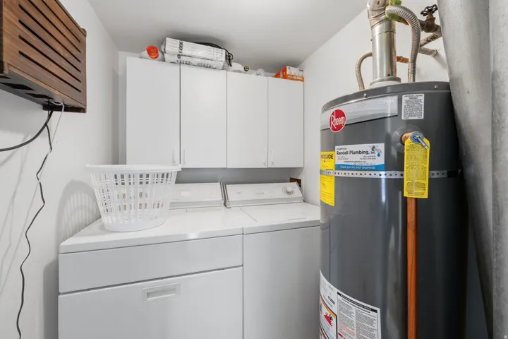 Dedicated laundry area featuring white cabinetry, a built-in countertop, and a water heater
