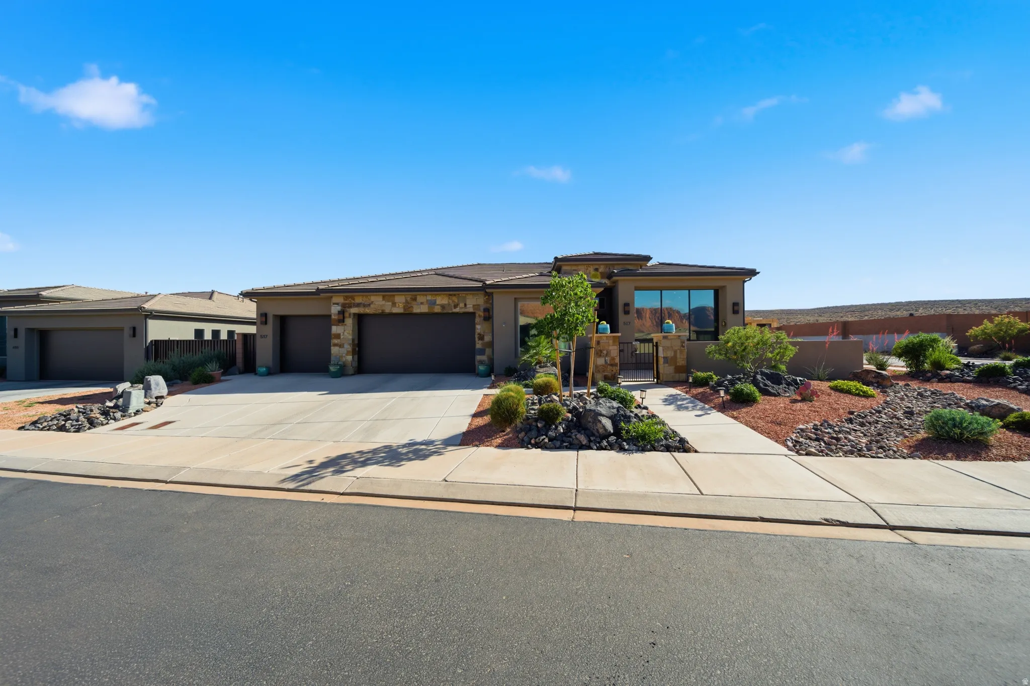 Modern desert-style residence with a two-car garage, stone façade accents, and a concrete driveway