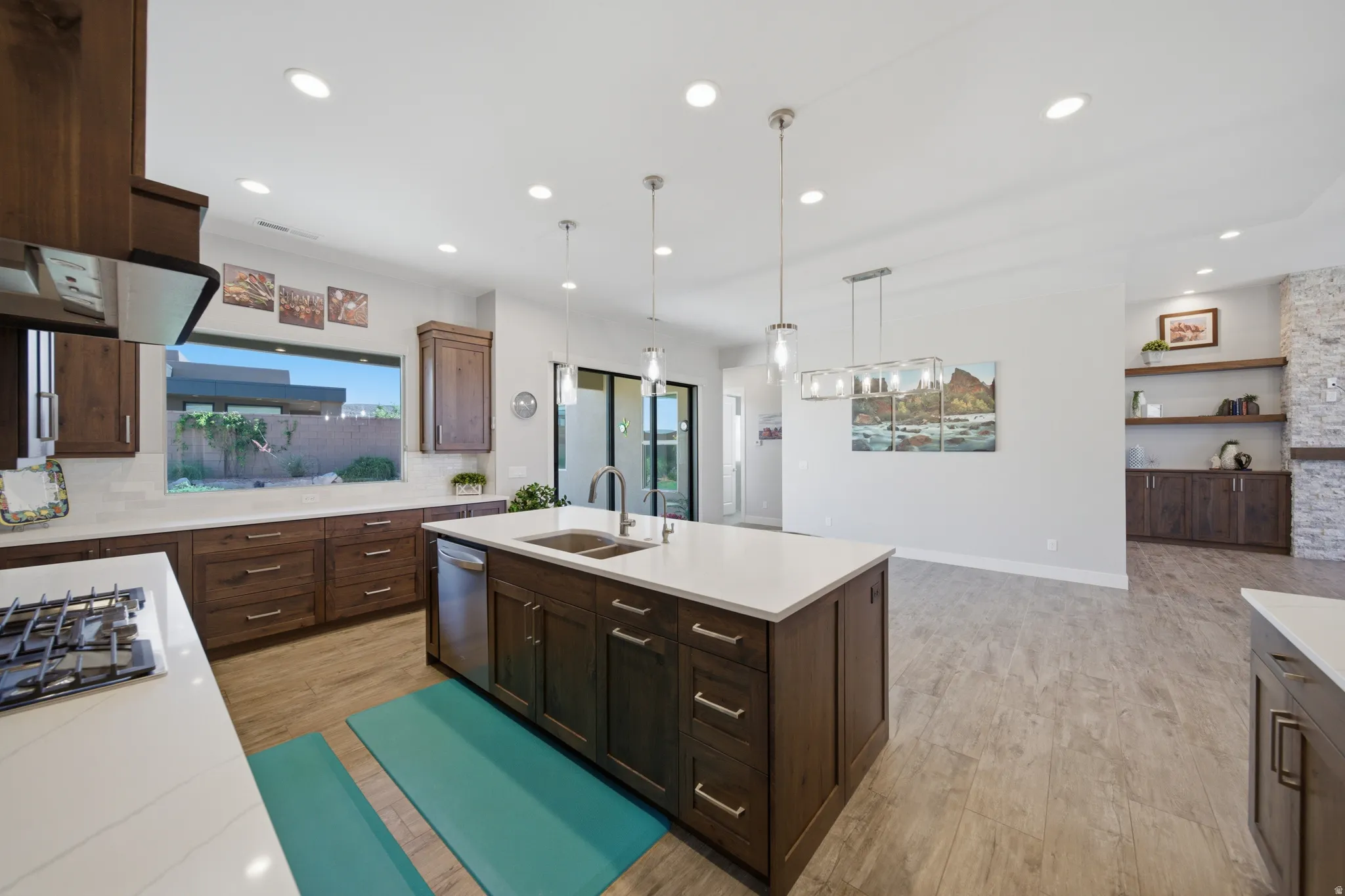 Modern kitchen featuring a large central island with a double basin sink, white countertops, and dark wood cabinetry