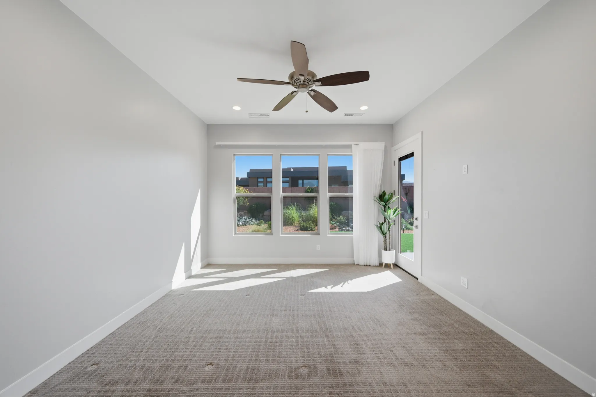 Spacious room featuring broad windows with white trim, recessed lighting, and a ceiling fan