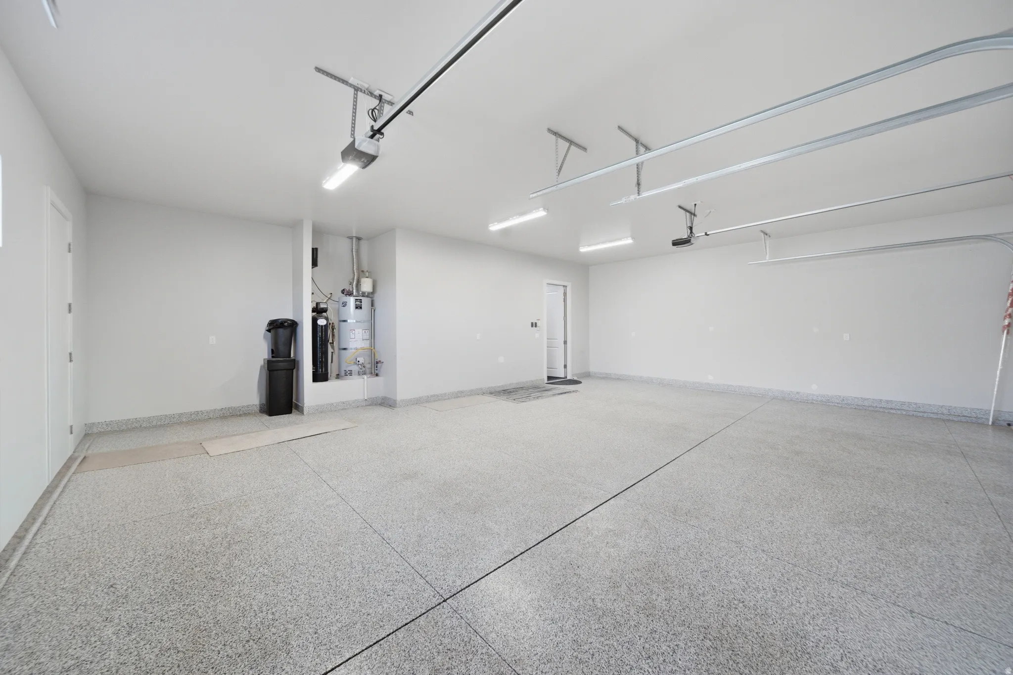 Spacious garage with epoxy flooring, white walls, and overhead track lighting