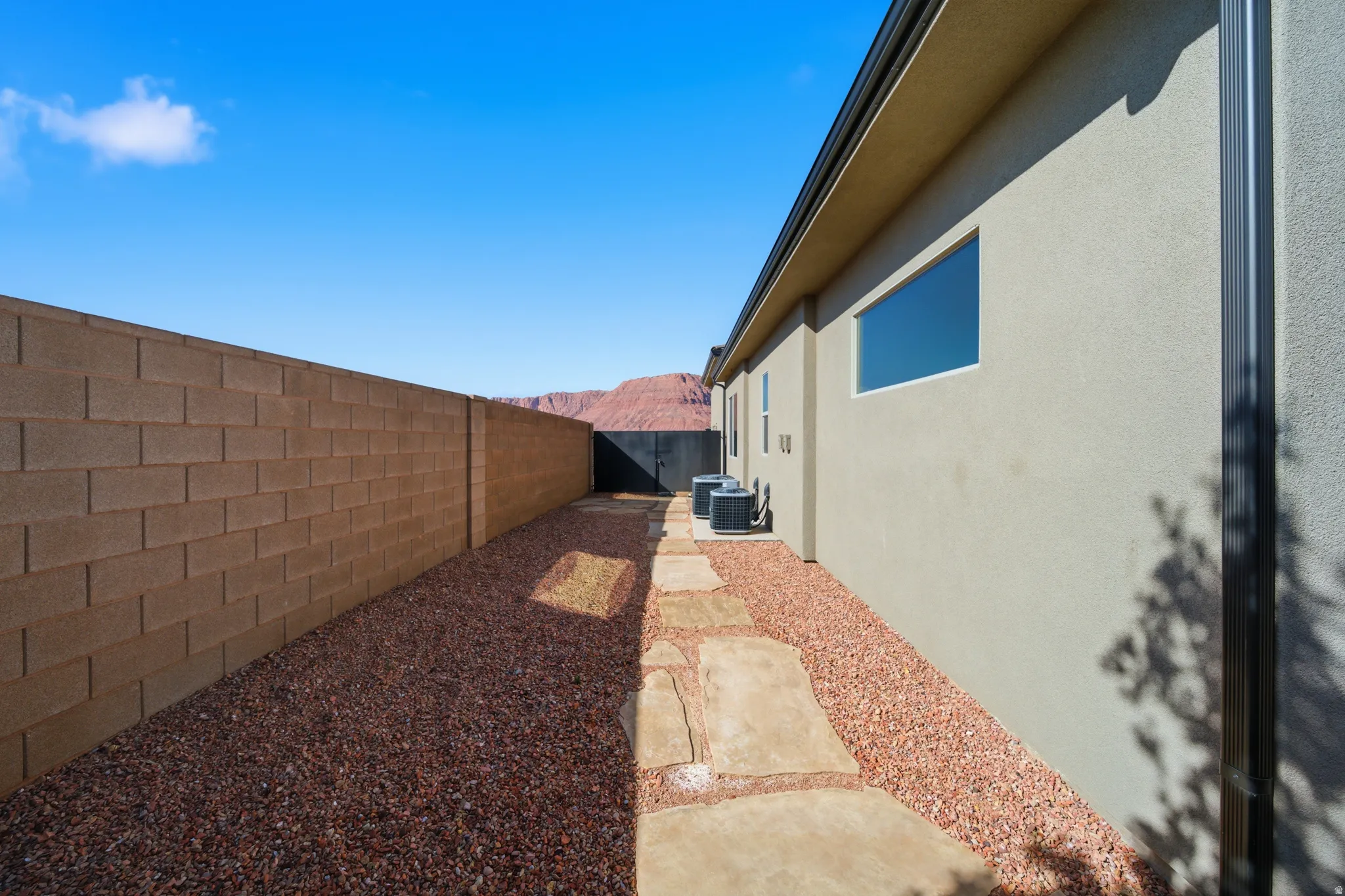 Side yard featuring a decorative gravel ground cover, concrete paver pathway, and a block wall perimeter