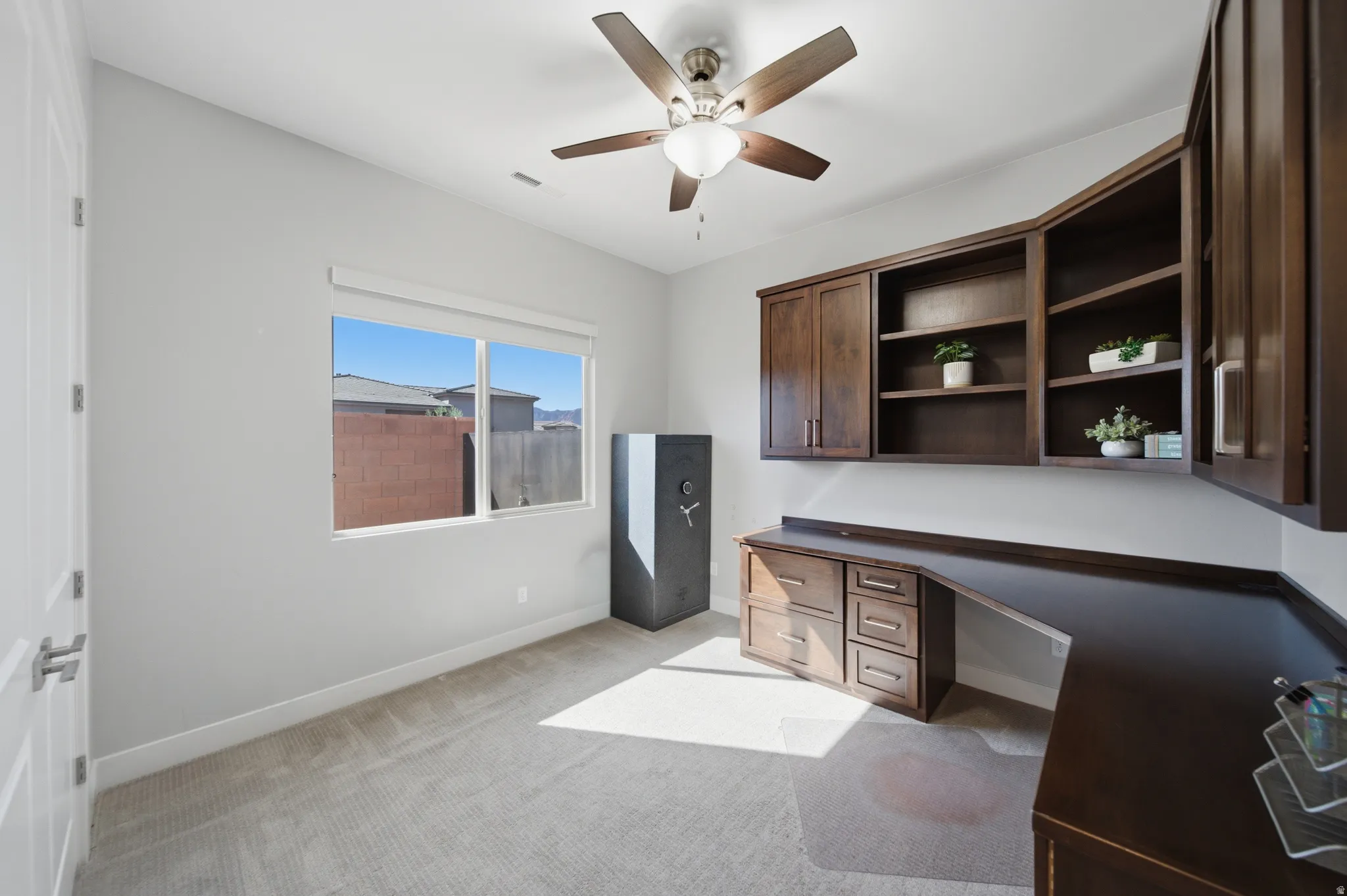 Room featuring built-in wood-finish cabinetry, a coordinated desk, and a ceiling fan with integrated lighting