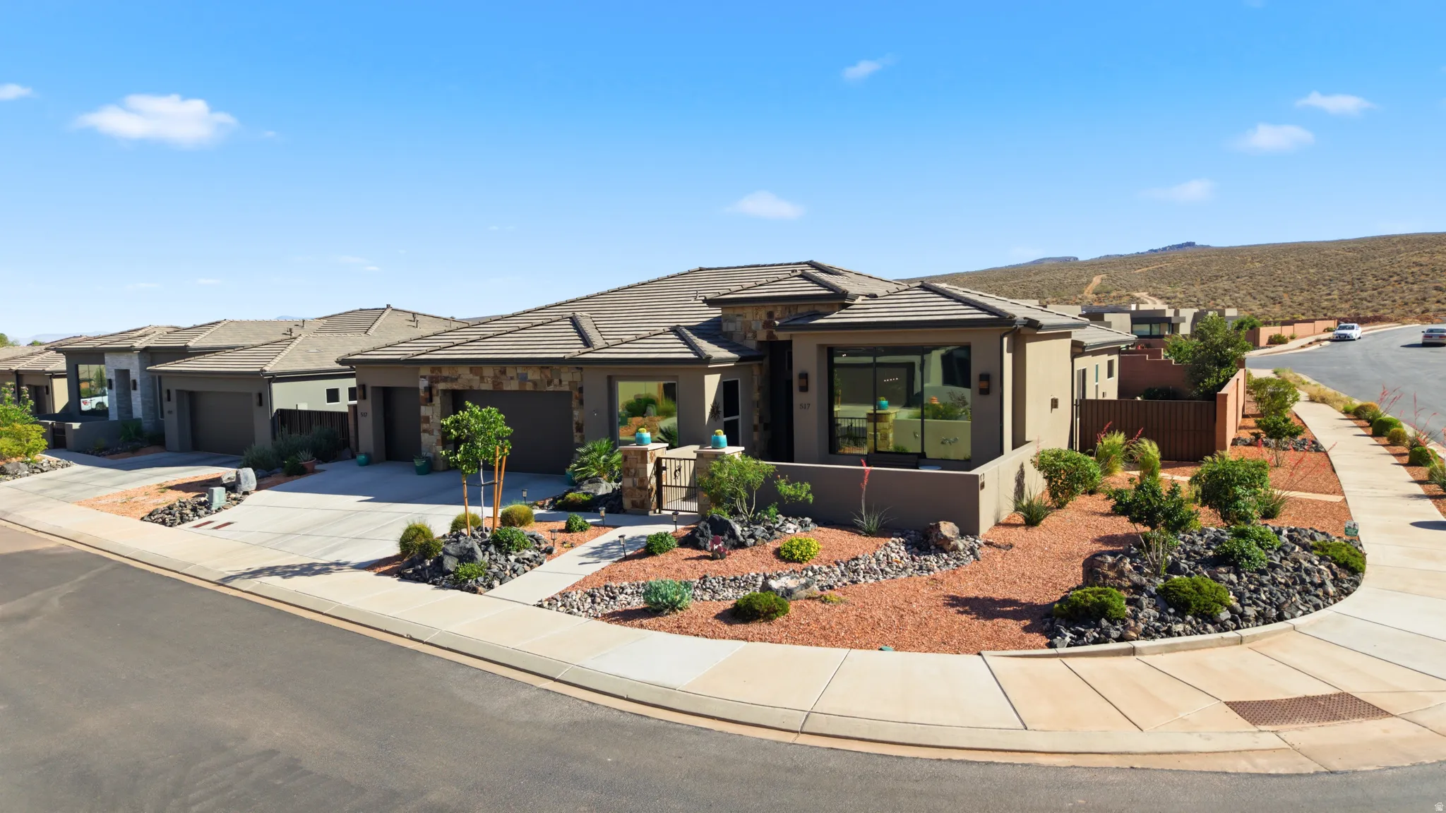 Contemporary single-story residence featuring a stucco and stone exterior, a tiled roof, a two-car garage, and desert landscaping