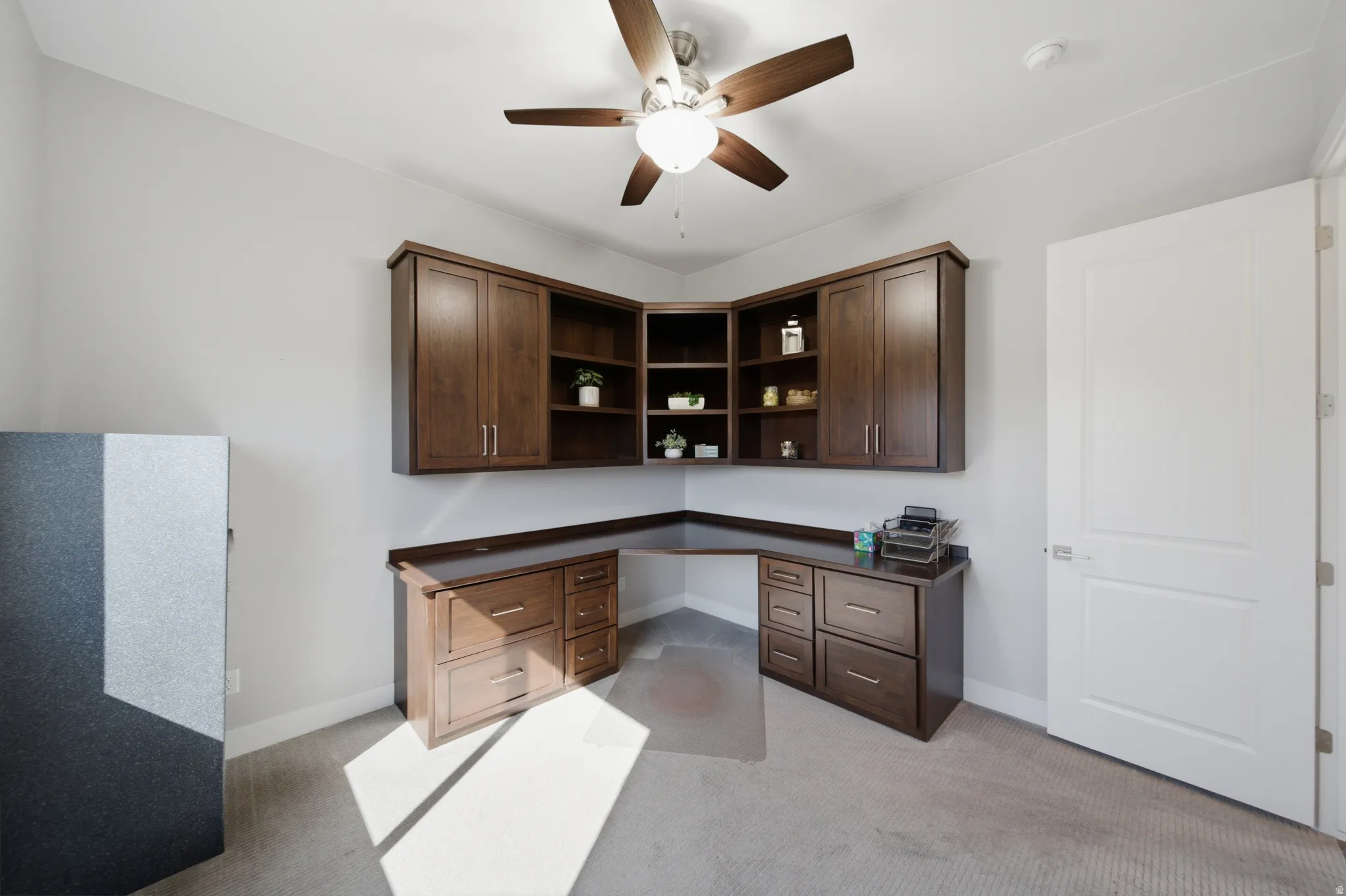 Built-in L-shaped desk with rich wood-finish cabinetry and overhead shelving