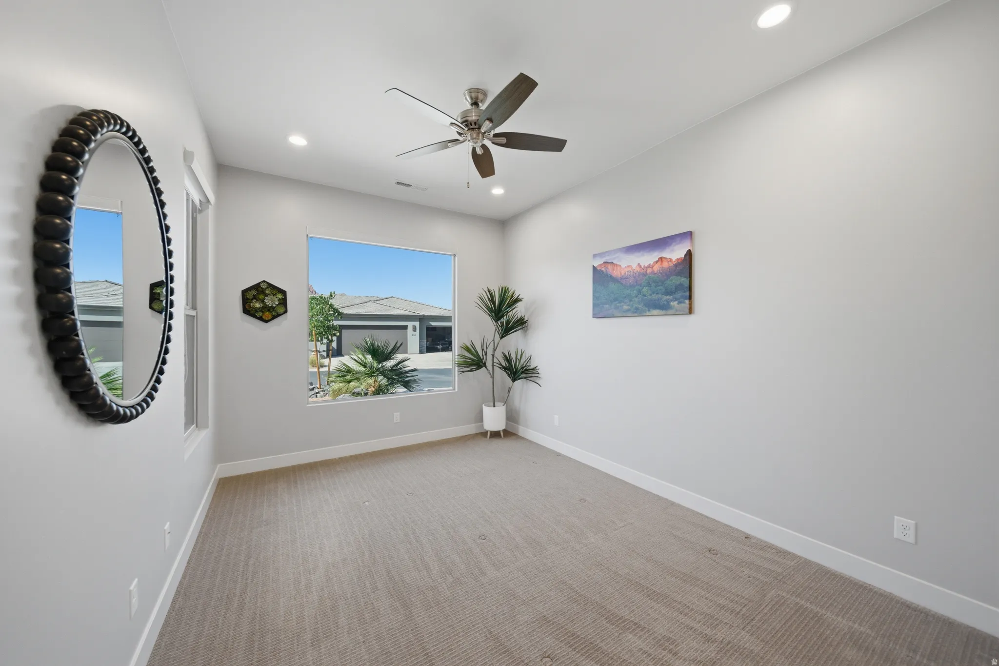 Spacious room featuring neutral carpet flooring, recessed lighting, and a modern ceiling fan