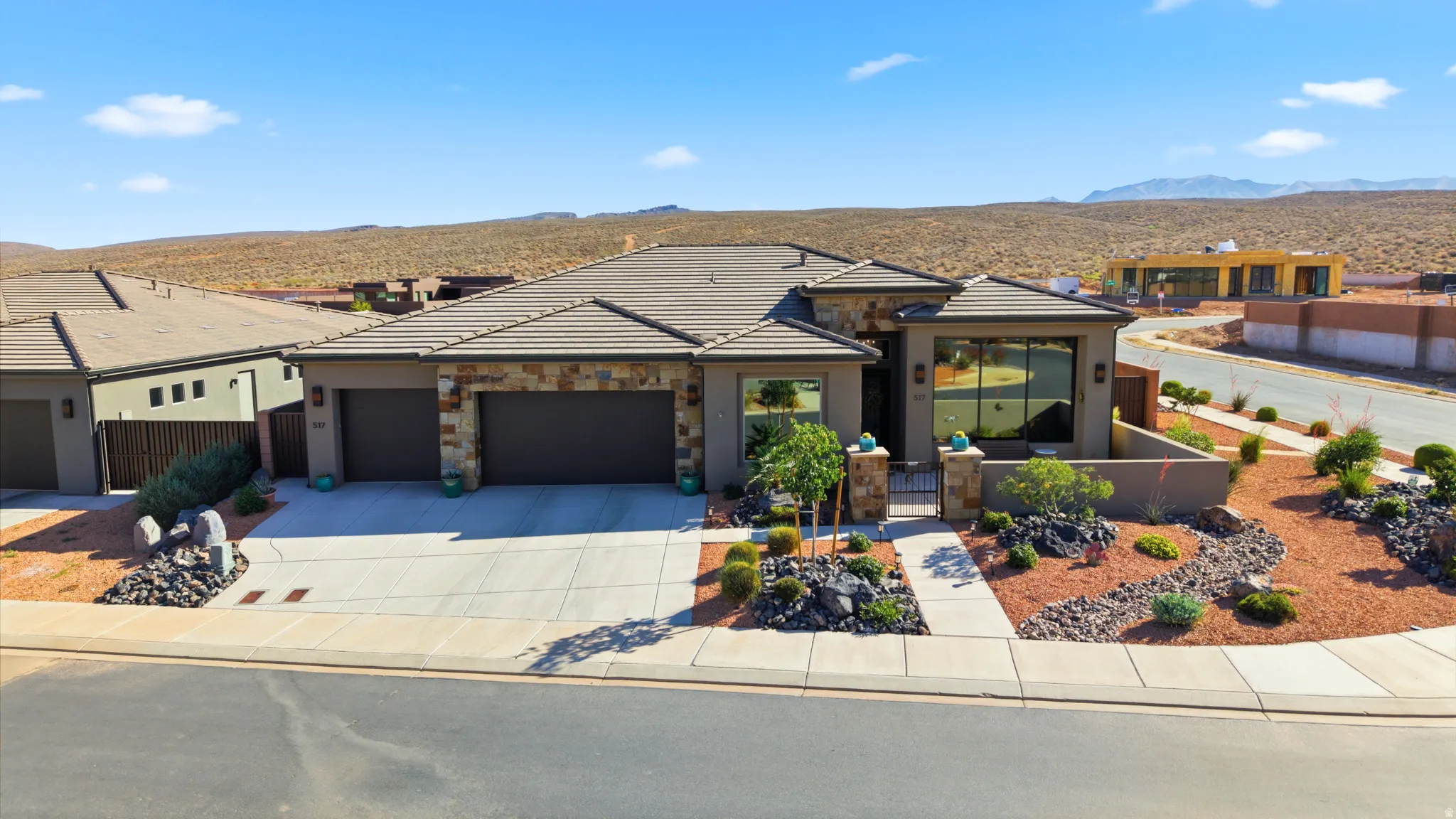 Desert-inspired architecture featuring a stone and stucco facade, a tiled roof, and an attached two-car garage