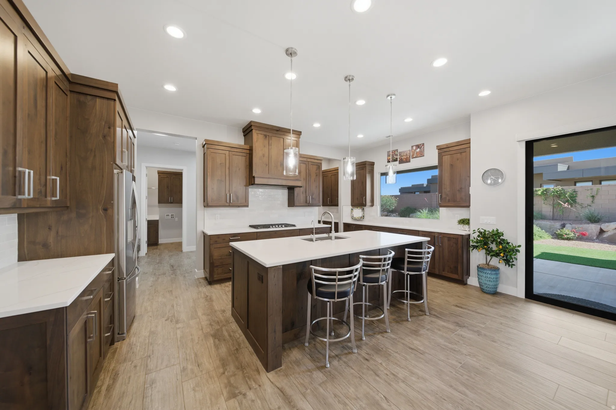 Spacious kitchen featuring an expansive center island with seating, wood-finish flooring, recessed lighting, and rich wood cabinetry