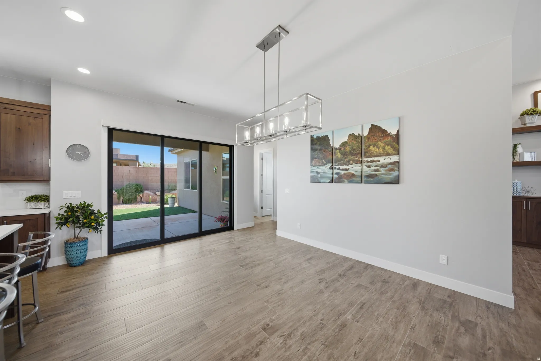 Spacious dining area featuring wood-finish flooring, a contemporary linear chandelier, and recessed lighting