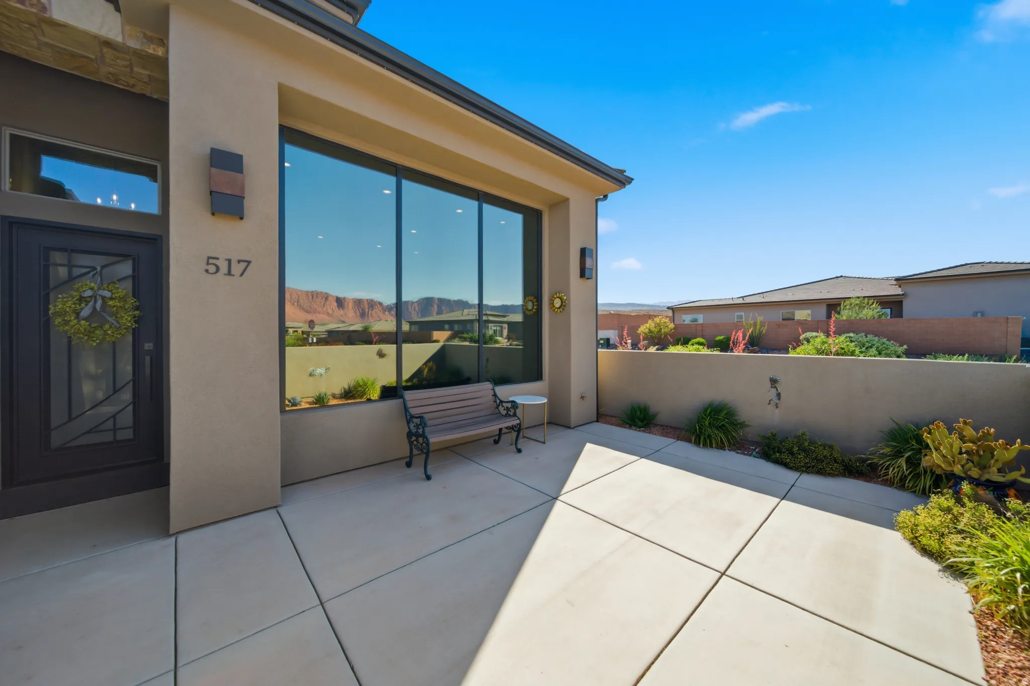 Contemporary stucco exterior with a large picture window, a dark-paneled entry door, and concrete patio