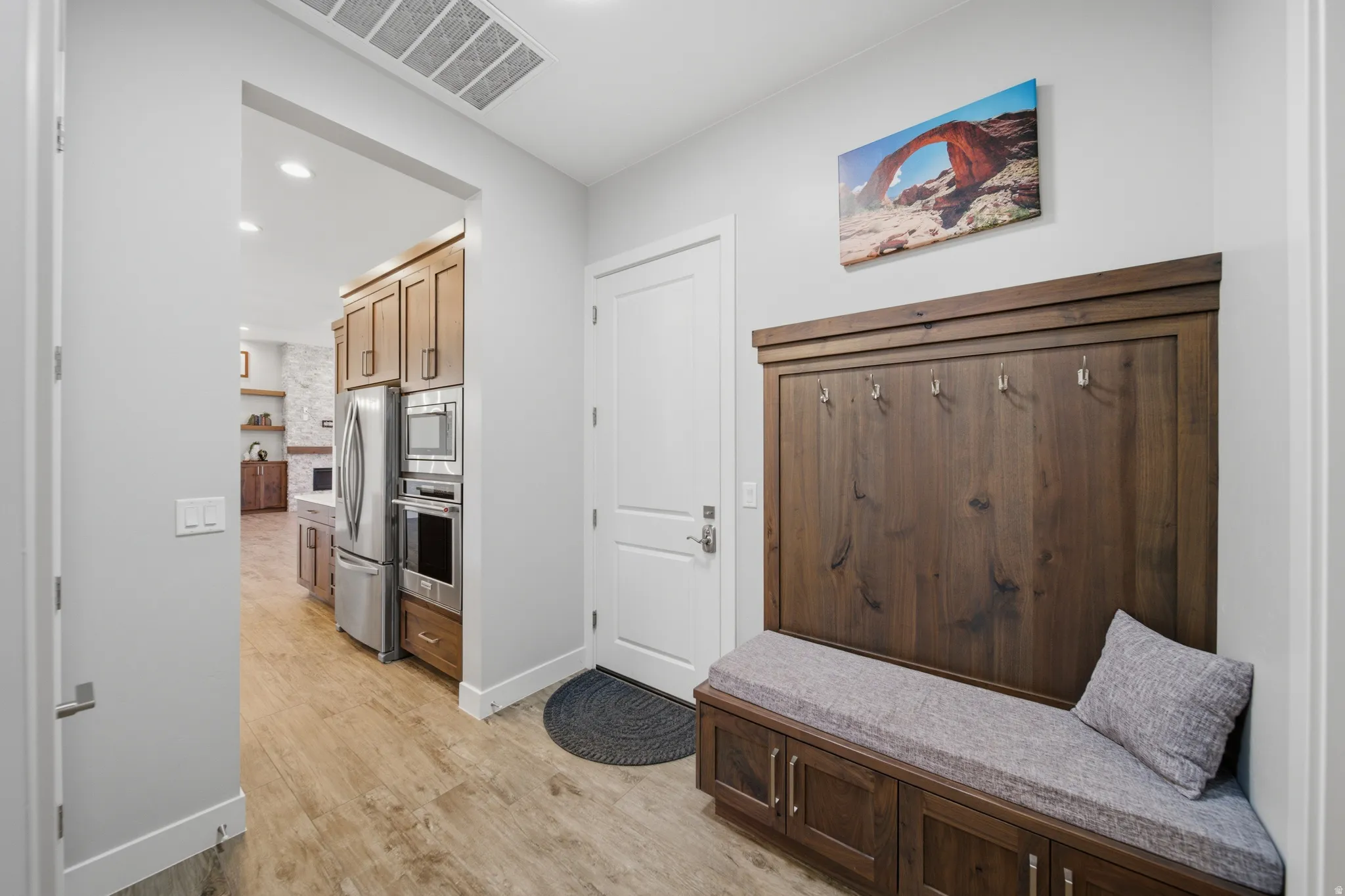 Entryway featuring a built-in wood-finish bench with storage, integrated coat hooks, and wood-finish flooring