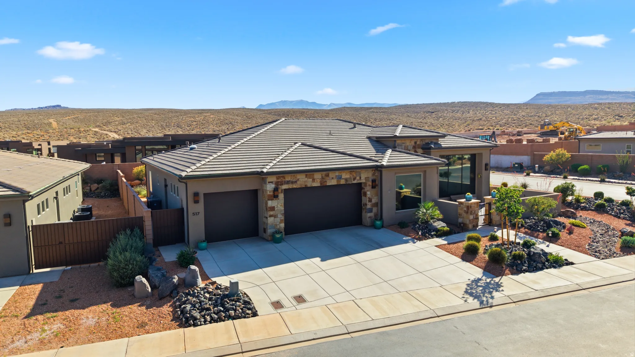 Contemporary ranch-style residence featuring a two-car garage, stone and stucco exterior, and a tile roof