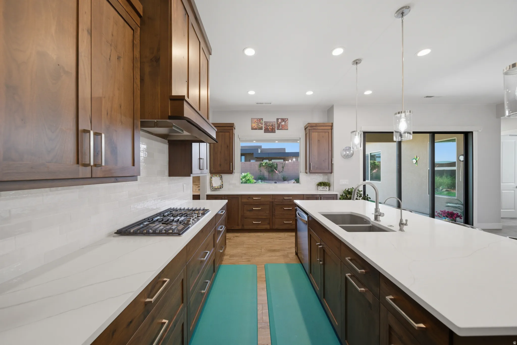Expansive kitchen with rich wood cabinetry, light-toned countertops, and a gas cooktop