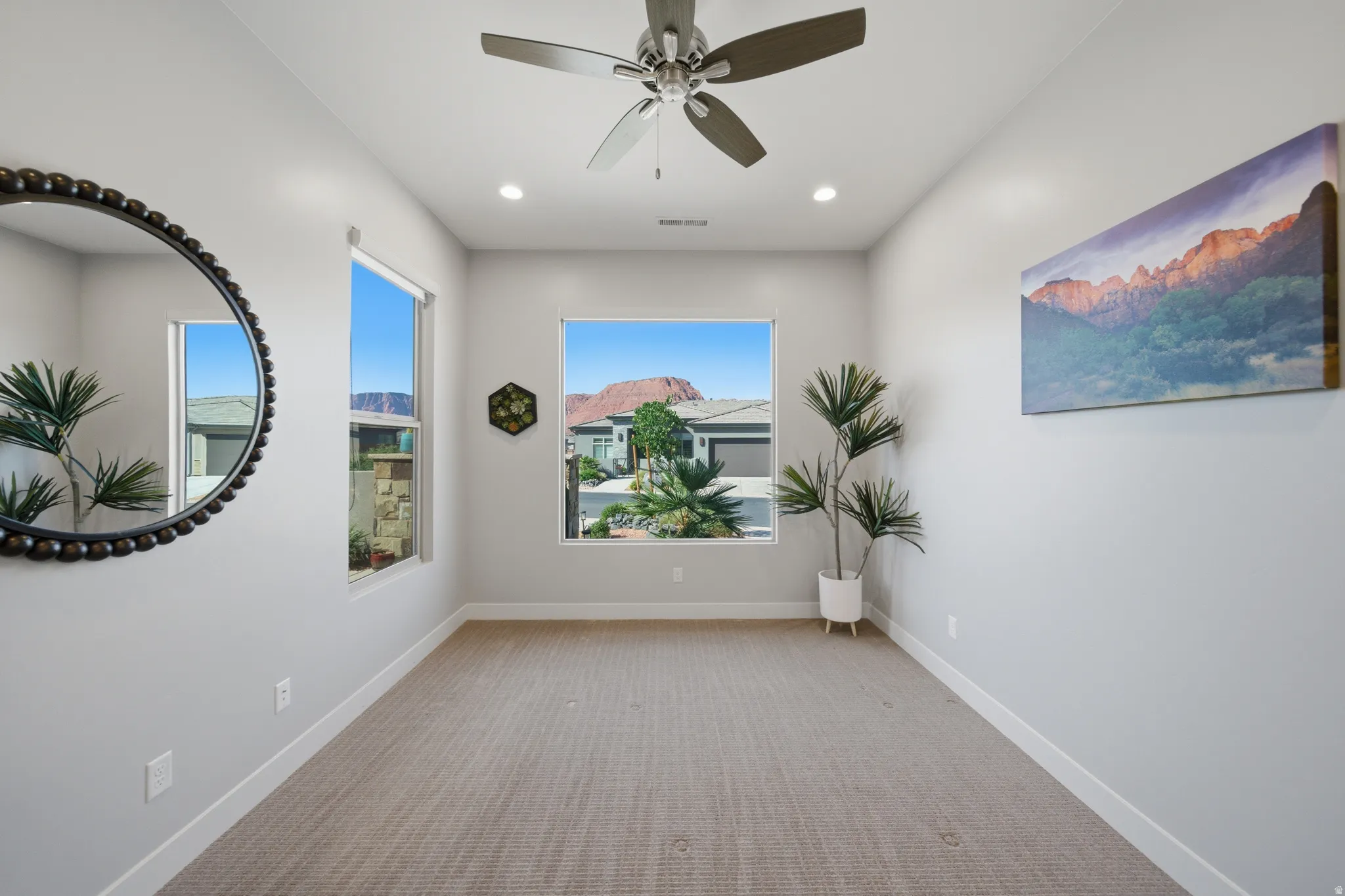 Spacious room featuring multiple windows, recessed lighting, a ceiling fan, and light-toned carpeting